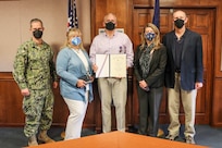 Group photo of John Hurley (center) being presented the Navy Meritorious Civilian Service Award
