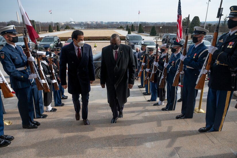 Secretary of Defense Lloyd J. Austin III walks up steps as military guard stand on either side.