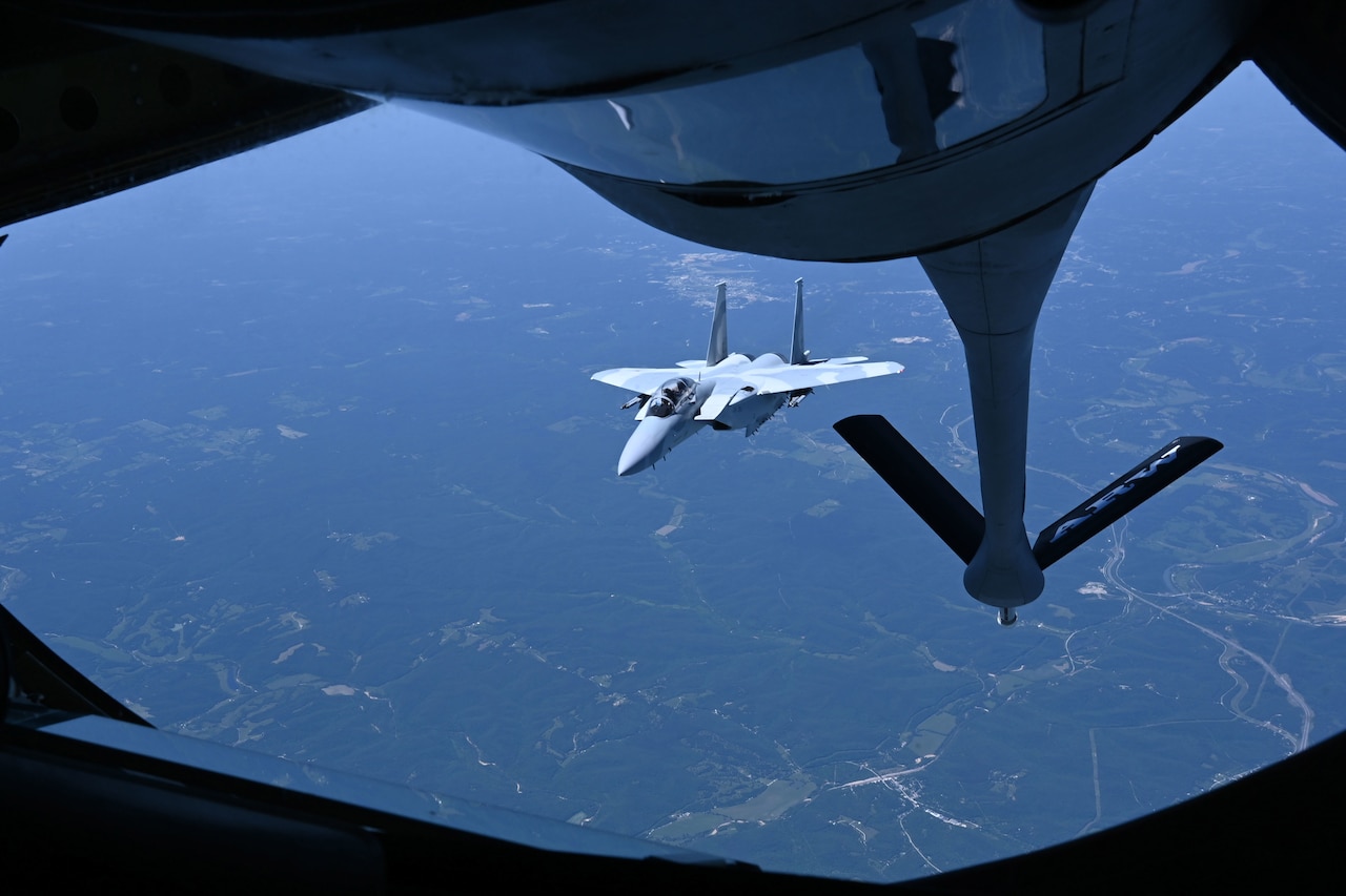 An aircraft is refueled mid-air via a tanker.