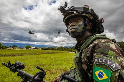 A Brazilian army soldier assigned to 5th Battalion, 12th Light Infantry (Air Assault), 2nd Division, kneels in the grass during Southern Vanguard 22 in Lorena, Brazil, Dec. 7, 2021. U.S. and Brazilian army soldiers took part in the air assault exercise, which was the largest deployment of a U.S Army unit to train with the Brazilian army forces in Brazil. (U.S Army photo by Pfc. Joshua Taeckens)