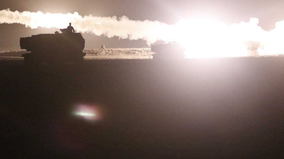 At night, smoke trails indicate the path of missiles that have been launched.  They and the salutes of combat vehicles are illuminated by the ignition of other rockets.