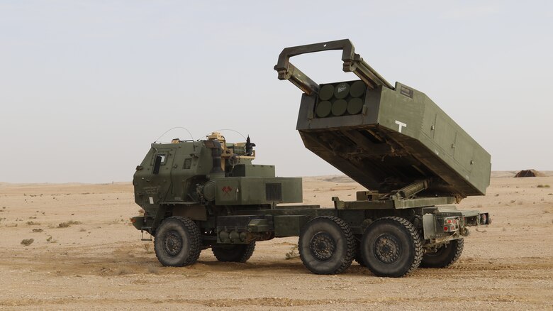 A military vehicle with rocket-launchers on the back sits in the desert.