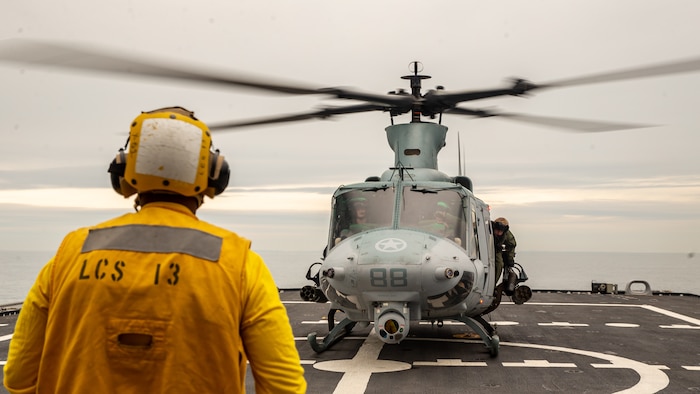 A U.S. Navy Sailor aboard the USS Wichita (LCS 13) guides a UH-1Y Venom helicopter onto a landing pad during Littoral Exercise I (LEX) on Jan. 25, 2022. During LEX I, Marines and Sailors are experimenting with new concepts and forces to prepare for future scenarios in littoral environments along the East Coast. LEX I is the first time a Blue-Green team conducted amphibious, ship-to-shore operations while embarked on a littoral combat ship. (U.S. Marine Corps photo by Cpl. Elijah J. Abernathy)