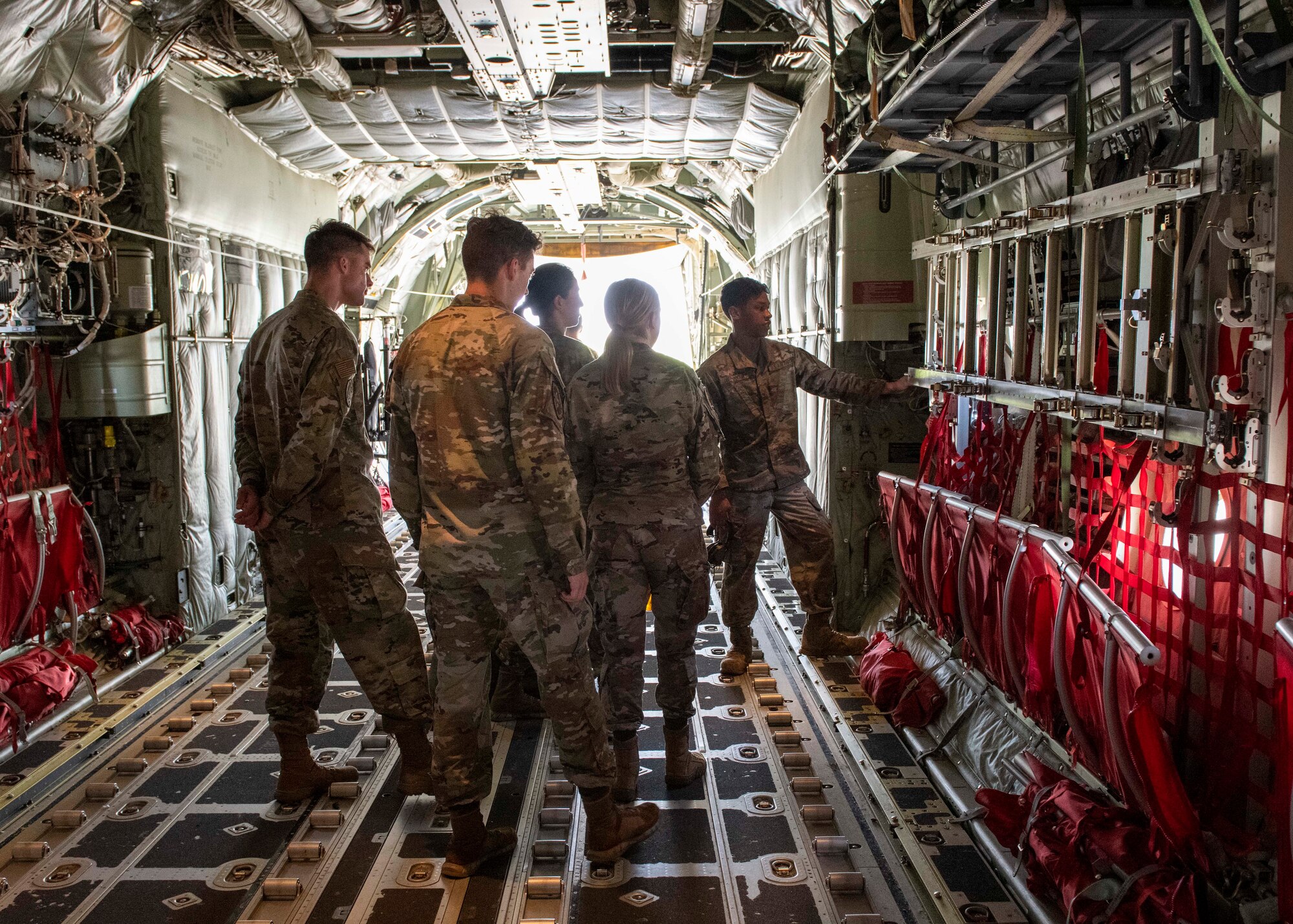 Four cadets are shown the interior of a cargo plane by a sergeant.