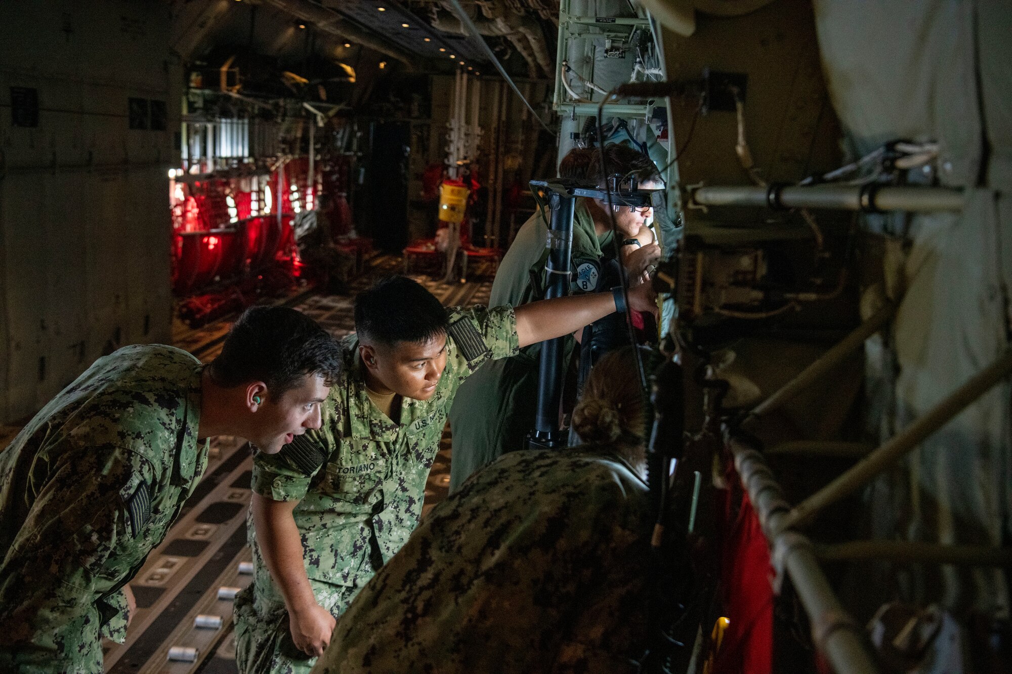 Two navy cadets look out a cargo plane window