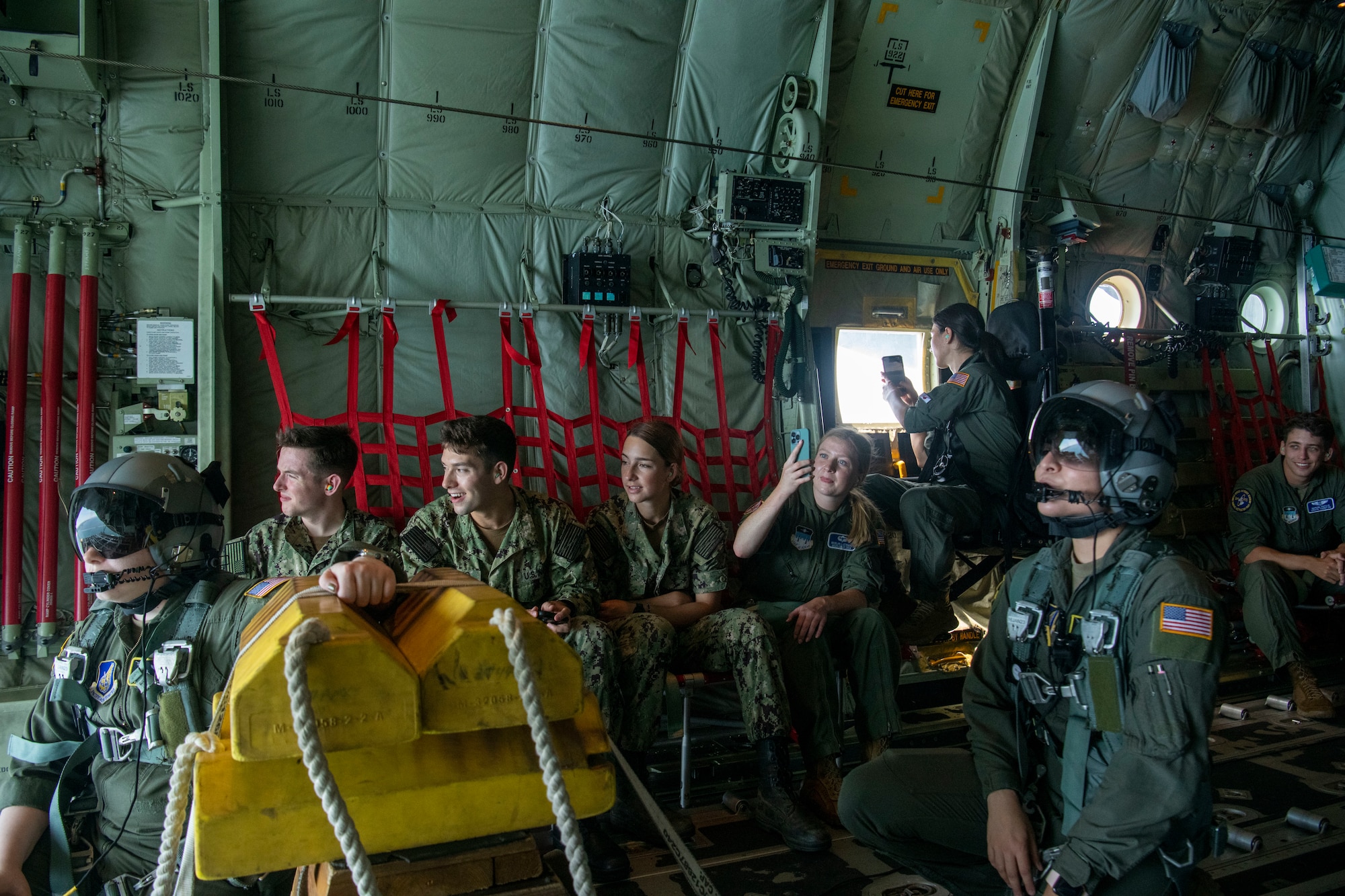 Several cadets and airmen look out the rear of a cargo plane in-flight.