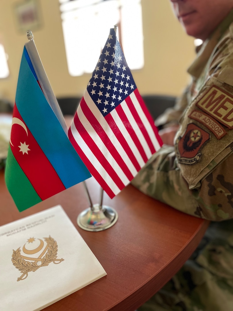 An air adviser with the 137th Special Operations Medical Group, Oklahoma Air National Guard, alongside the flags of the United States and Azerbaijan during a State Partnership Program visit with Azerbaijan Operational Capabilities Concept Battalion doctors and medical noncommissioned officers in Baku, Azerbaijan, conducted June 20-24, 2022. The 137th SOMDG learned how the Azerbaijan military trains its troops for combat medical response and will develop doctrine the Azerbaijan military can use to work toward becoming interoperable with NATO forces.