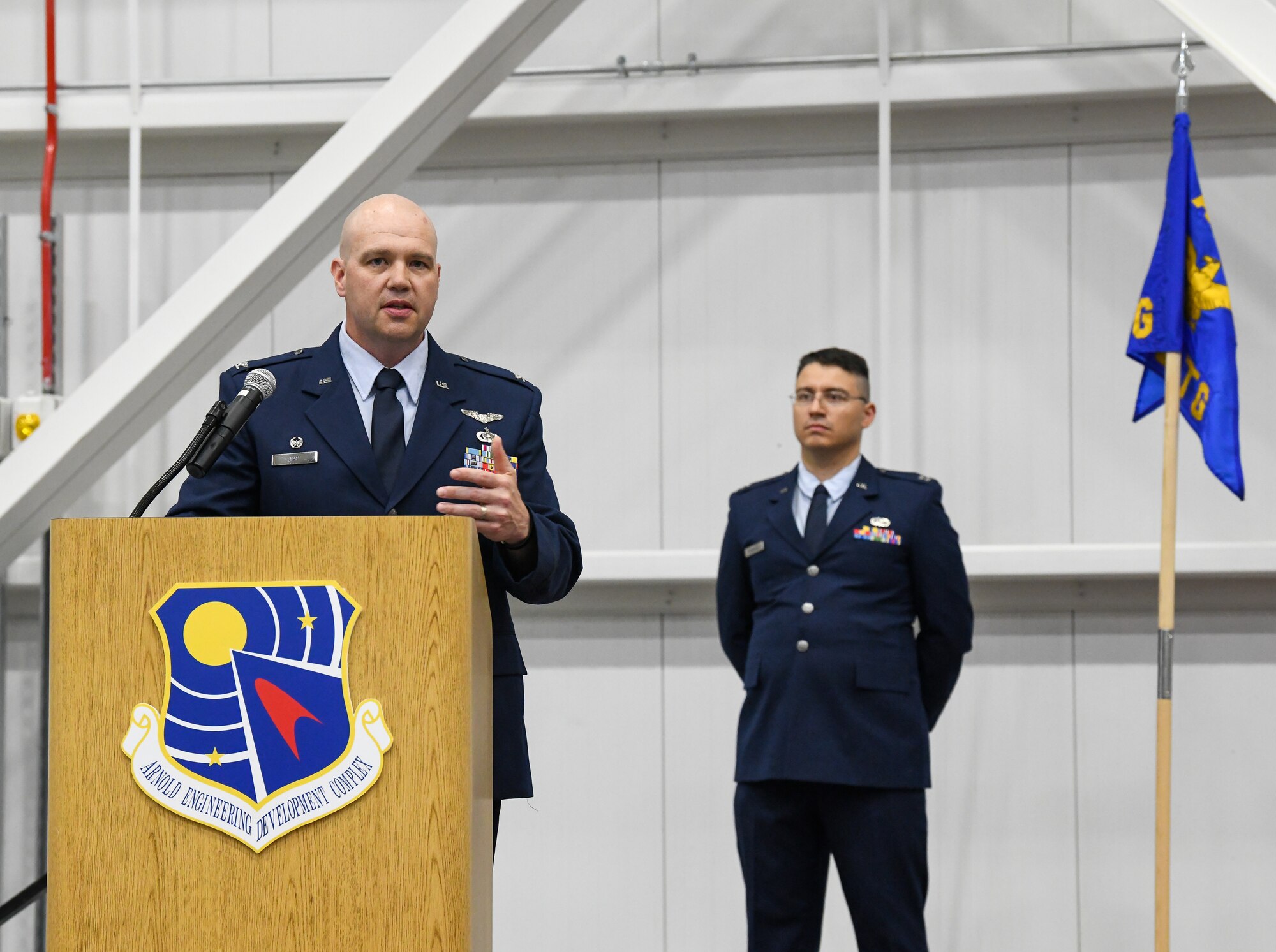Col. Jason Vap, commander of the 804th Test Group, Arnold Engineering Development Complex, speaks after assuming command of the 804 TG during a change of command ceremony June 21, 2022, in the Aircraft Test Support Facility at Arnold Air Force Base, Tennessee. Also pictured is Capt. Christopher Fernandez, guidon bearer. (U.S. Air Force photo by Jill Pickett)