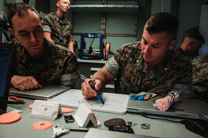 U.S. Marine Corps Lance Cpl. Gregory Bogdan, an aircraft hydraulic mechanic, and Maj. Tom O’Bryon, an aviation supply officer, both with Marine Aviation Logistics Squadron 49, Marine Aircraft Crew 49, 4th Marine Aircraft Wing, design a bridge concept during an advanced additive manufacturing course at Stewart Air National Guard Base, Newburgh, N.Y., June 23, 2022. The Marine Innovation Unit and the II Marine Expeditionary Force (MEF) Innovation Campus mobile training team, staffed by U.S. Marines with 2nd Marine Logistics Group, facilitated training that enables Marines to produce innovative solutions, solve maintenance issues, and develop capabilities to defeat new and emerging threats. (U.S. Marine Corps photo by Lance Cpl. Sixto Castro)