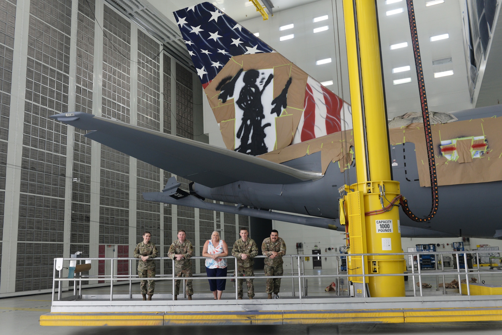A team of 157th Air Refueling Wing maintenance Airmen, along with professional aircraft artist Shayne Meder, pause for a moment in front of their nearly complete custom paint job on the tail of a wing KC-46A, at the 176th Wing's paint booth, Joint Base Elmendorf-Richardson, June 29. From left to right: Airman 1st Class Rebekka Bloser, Tech. Sgt. Jay Cunha, Master Sgt. (retired) Shayne Meder, Staff Sgt. Kevin Canney, Staff Sgt. Cory Lewis. (U.S. Air National Guard photo by Senior Master Sgt. Timm Huffman)