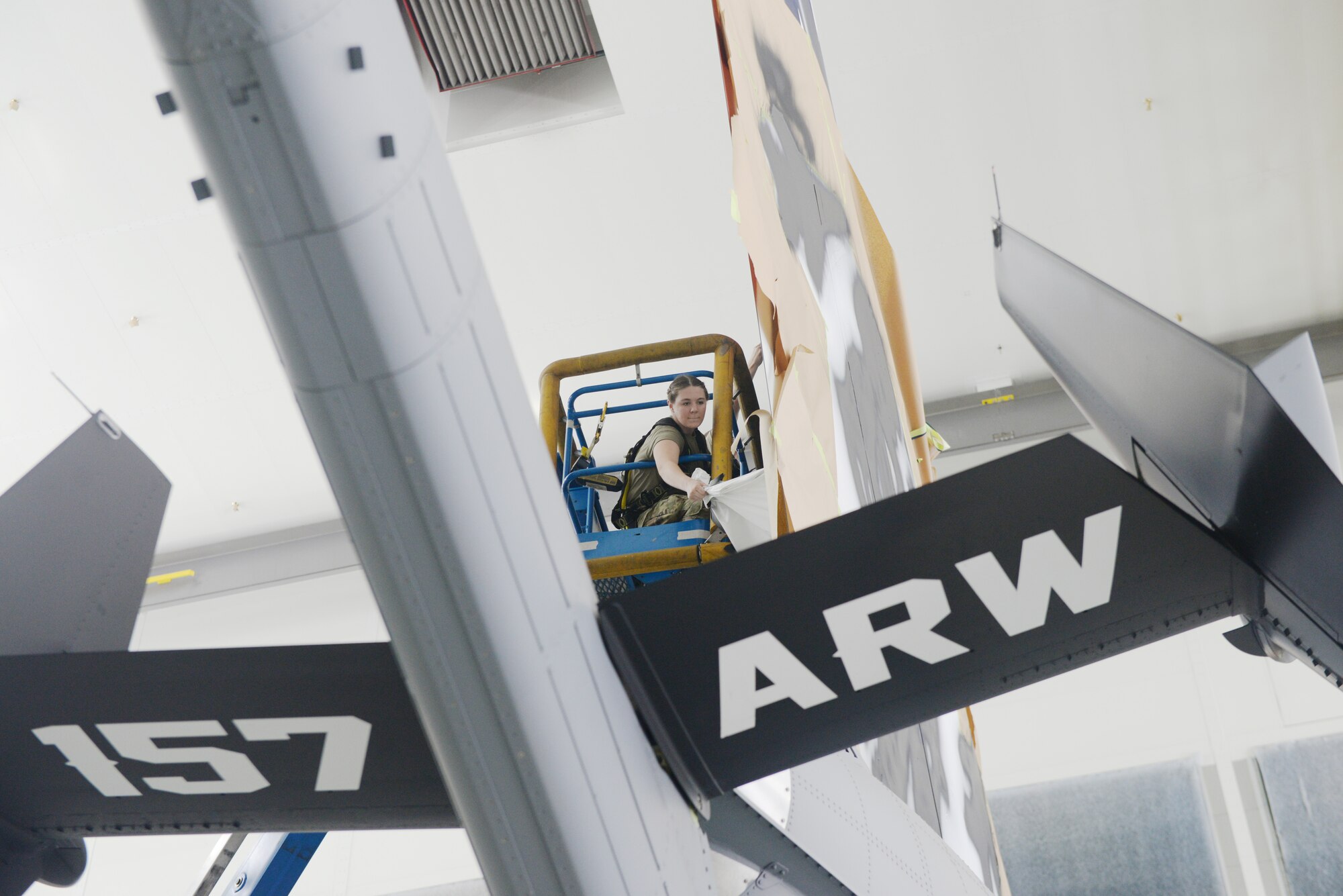 Airman 1st Class Rebekka Bloser, a 157th Air Refueling Wing structural aircraft maintenance Airmen, carefully removes paint masking from the Spirit of Portsmouth, a KC-46A which had just received a new custom paint job, Joint Base Elmendorf-Richardson, Alaska, June 29, 2022.