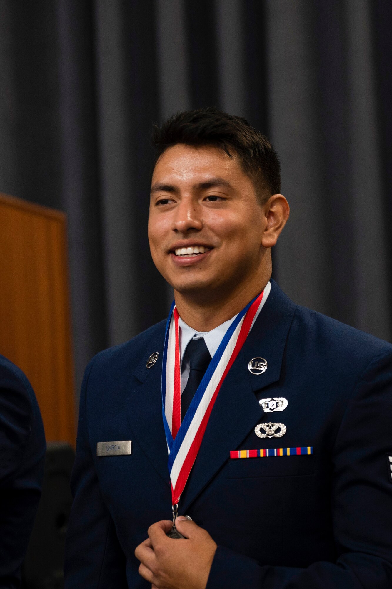 An Airman smiles and holds a medal