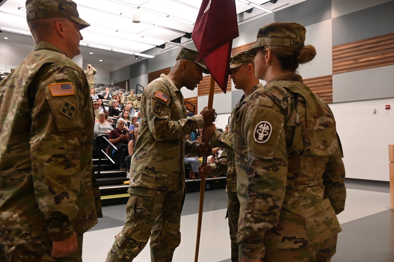 Col. Tracy Michael (left center), Fort George G. Meade Medical Department Activity commander, passes the unit guidon to Lt. Col. Christopher Richelderfer (right center), incoming commander of Barquist Army Health Clinic, at a change of command ceremony June 14, 2022, Fort Detrick, Maryland. Lt. Col. Christopher Richelderfer assumed command of  the clinic from Lt. Col. Johnathan Evans.