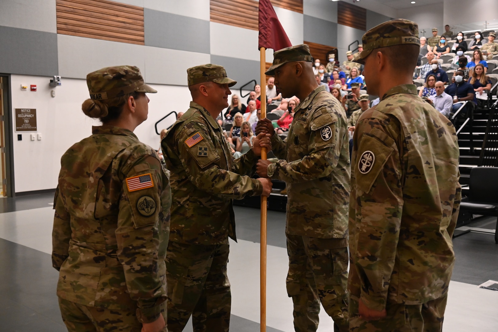 Promotable Lt. Col. Johnathan Evans (center left), outgoing commander of Barquist Army Health Clinic, passes the unit guidon to Col. Tracy Michael (center right), Fort George G. Meade Medical Department Activity commander, at a change of command ceremony June 14, 2022, Fort Detrick, Maryland. Lt. Col. Christopher Richelderfer assumed command of Barquist Army Health Clinic.