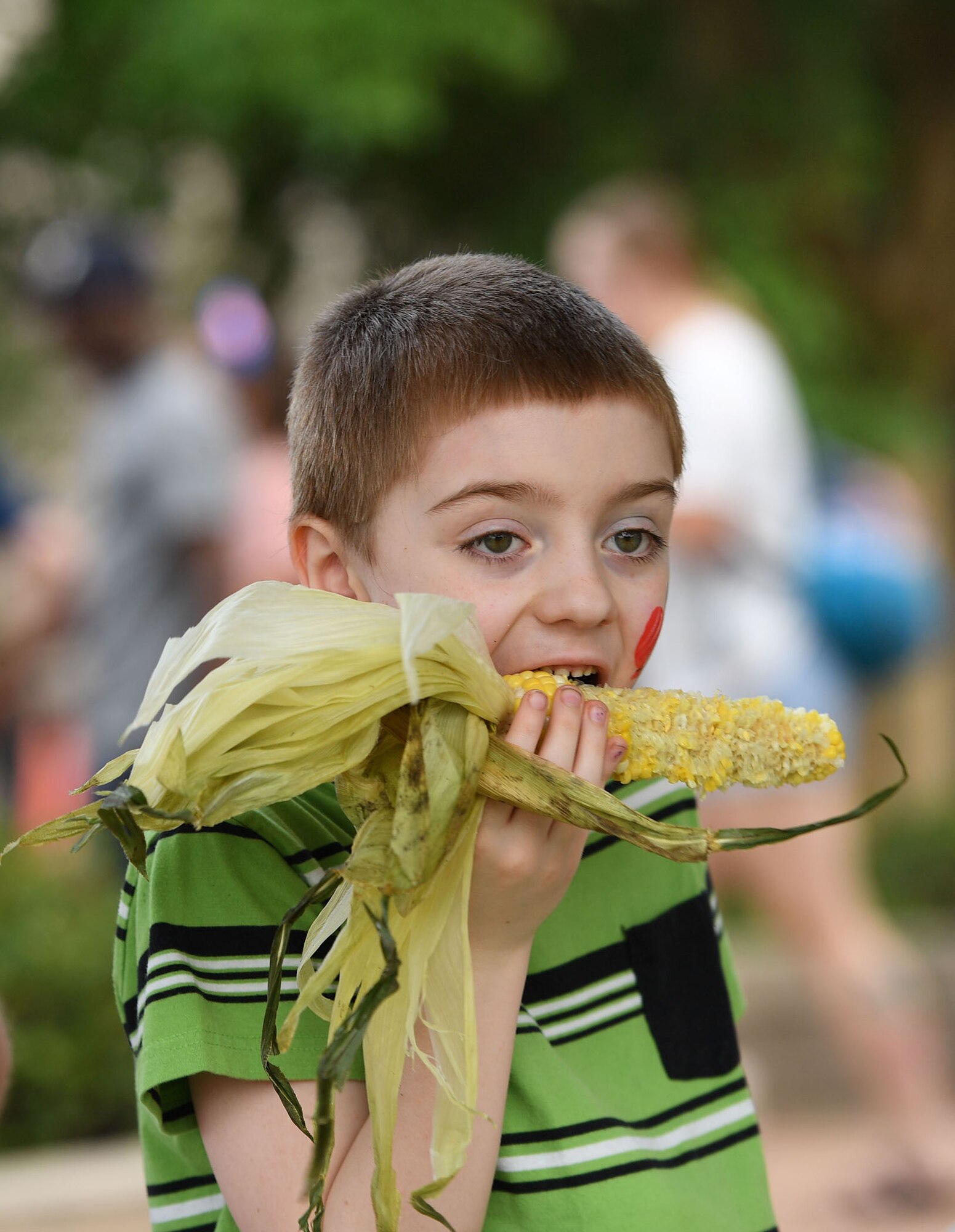 Cohen Pineda, son of U.S. Air Force 2nd Lt. Christopher Pineda, 333rd Training Squadron student, eats a piece of street corn during Freedom Fest at the Bay Breeze Event Center on Keesler Air Force Base, Mississippi, June 30, 2022. The event included a hot wings eating contest, a frozen mullet toss competition and fireworks. (U.S. Air Force photo by Kemberly Groue)