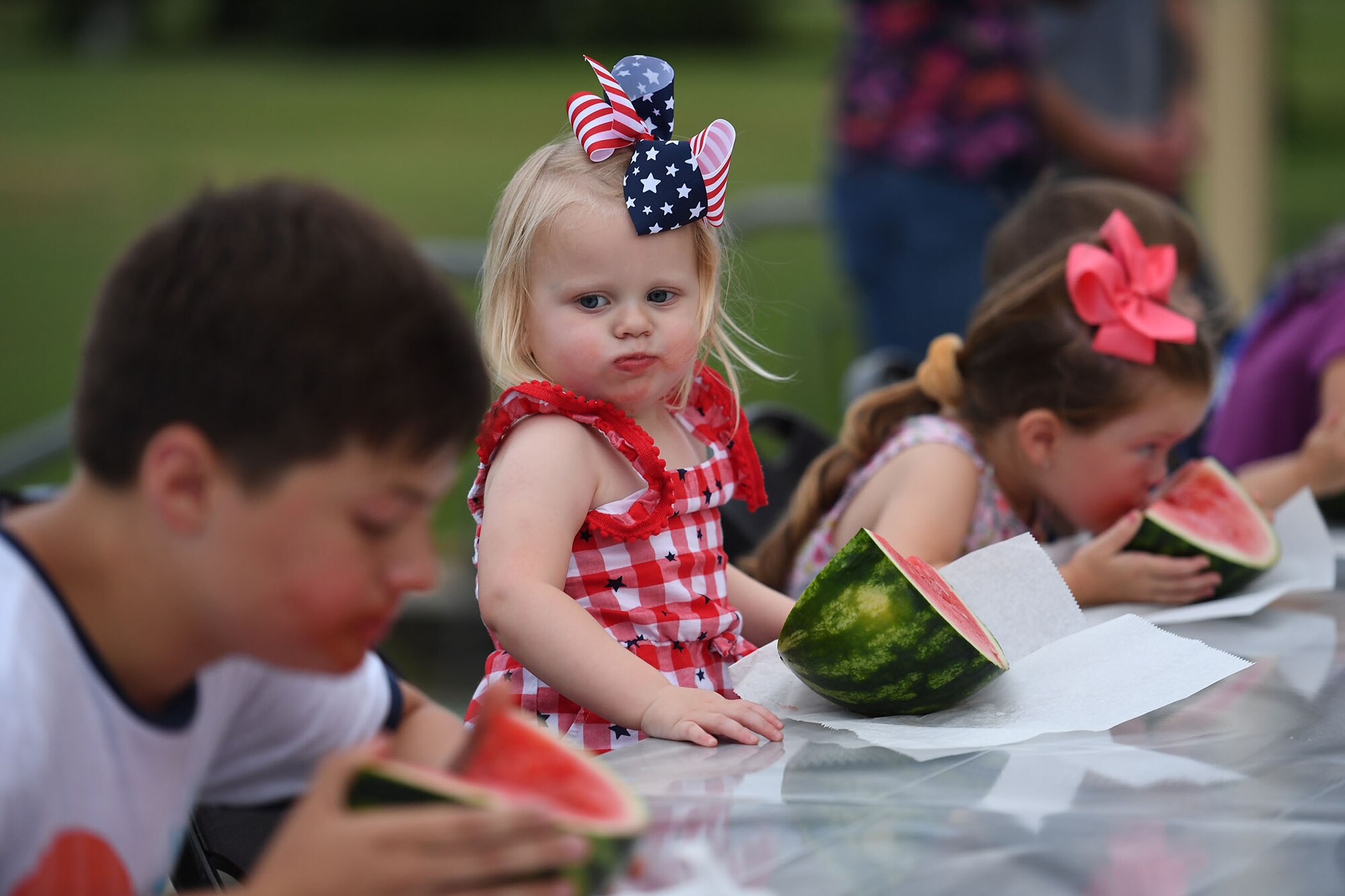 Holland Foster, daughter of U.S. Navy Lt. Sarah Foster, Naval Construction Group 2 staff judge advocate, Gulfport, Mississippi, participates in a watermelon eating contest during Freedom Fest at the Bay Breeze Event Center on Keesler Air Force Base, Mississippi, June 30, 2022. The event also included a hot wing eating contest, a frozen mullet toss competition and fireworks. (U.S. Air Force photo by Kemberly Groue)