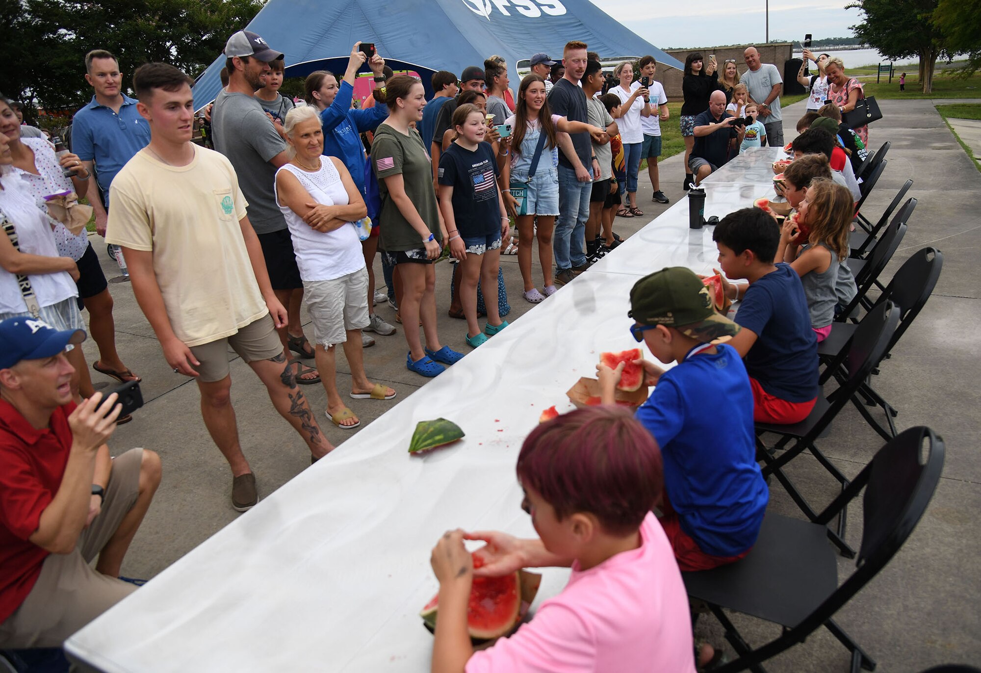 Keesler personnel and families gather to watch a watermelon eating contest during Freedom Fest at the Bay Breeze Event Center on Keesler Air Force Base, Mississippi, June 30, 2022. The event also included a hot wing eating contest, a frozen mullet toss competition and fireworks. (U.S. Air Force photo by Kemberly Groue)