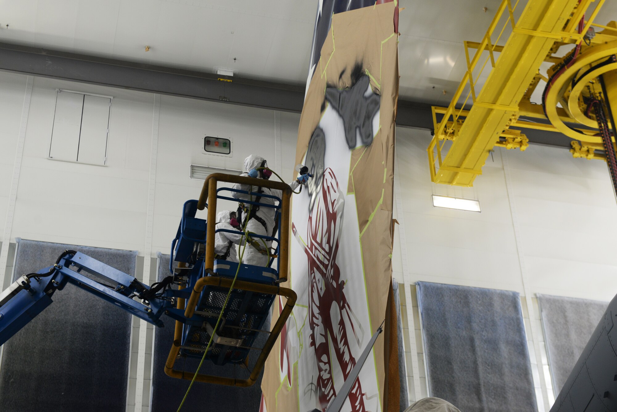 Staff Sgt. Cory Lewis, a 157th Air Refueling Wing structural maintenance Airman, paints a 16-foot-tall Minute Man on the tail of the Spirit of Portsmouth, a KC-46A assigned to the wing, while fellow maintainer Tech. Sgt. Jay Cunha looks on, during a temporary duty assignment to Joint Base Elmendorf-Richardson, Alaska, June 29, 2022.