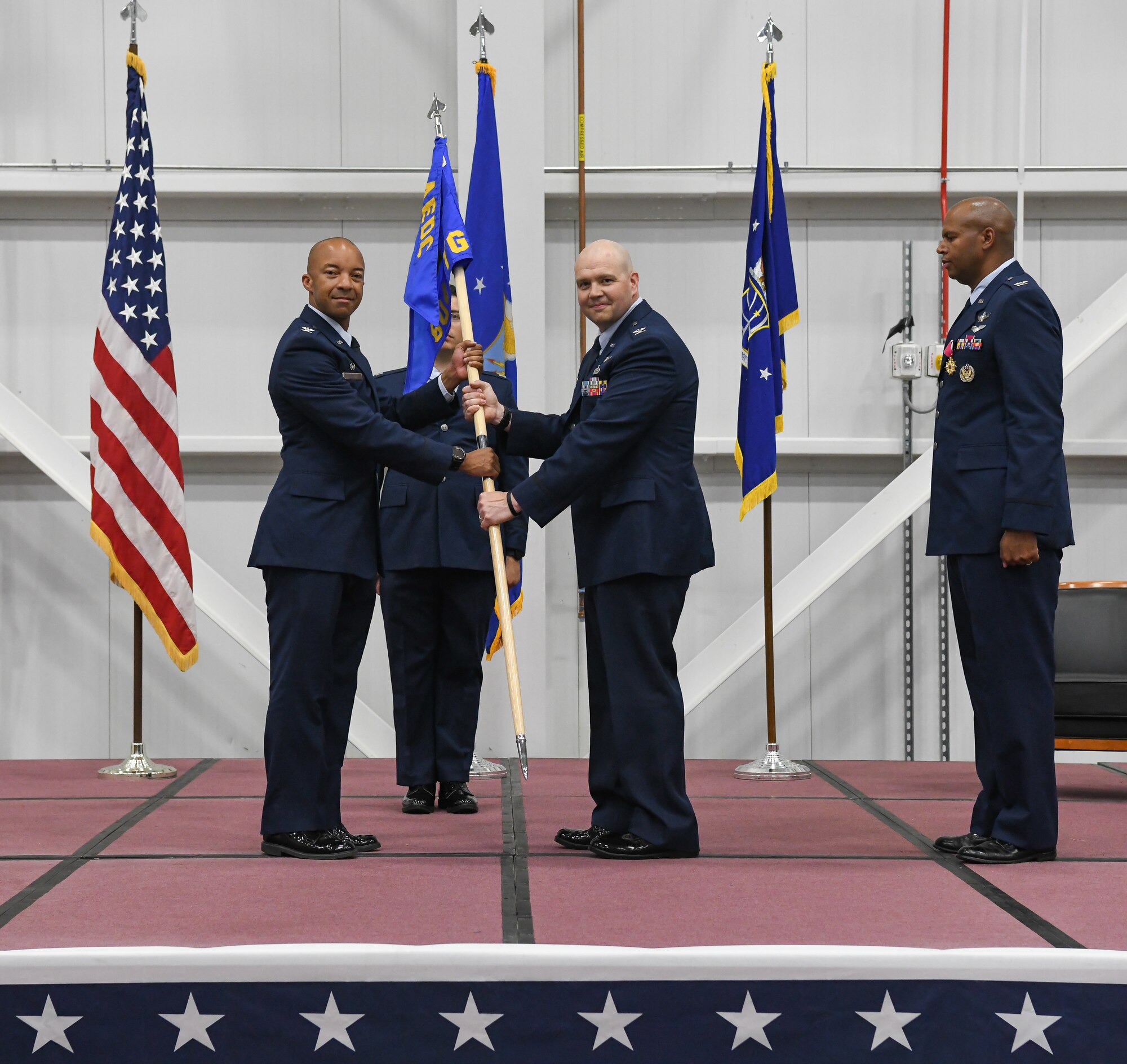 Arnold Engineering Development Complex Commander Col. Randel Gordon, left, passes the 804th Test Group guidon to Col. Jason Vap charging him with command of the group during a change of command ceremony June 21, 2022, in the Aircraft Test Support Facility at Arnold Air Force Base, Tennessee. Also pictured are Col. Linc Bonner, right, previous 804 TG commander, and Capt. Christopher Fernandez, guidon bearer. (U.S. Air Force photo by Jill Pickett)
