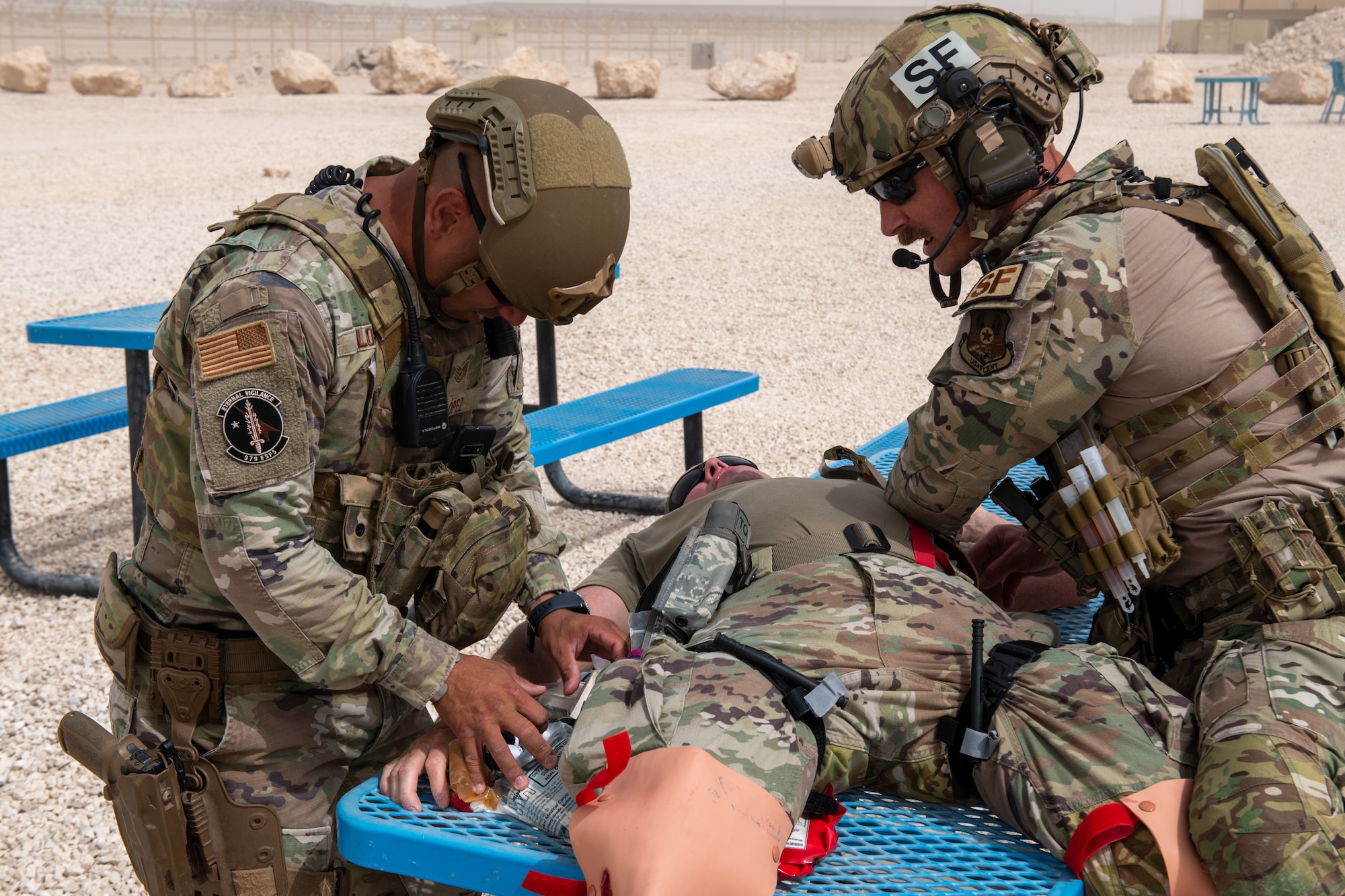 U.S. Air Force Tech. Sgt. Edward Lopez and U.S. Air Force Tech. Sgt. Johnathan Finer, 379th Expeditionary Security Forces Squadron members, apply first aid to a simulated explosion casualty during an exercise on Al Udeid Air Base, Qatar, June 27, 2022. The simulated casualty had massive bleeding from both of his legs. (U.S. Air National Guard photo by Airman 1st Class Constantine Bambakidis)