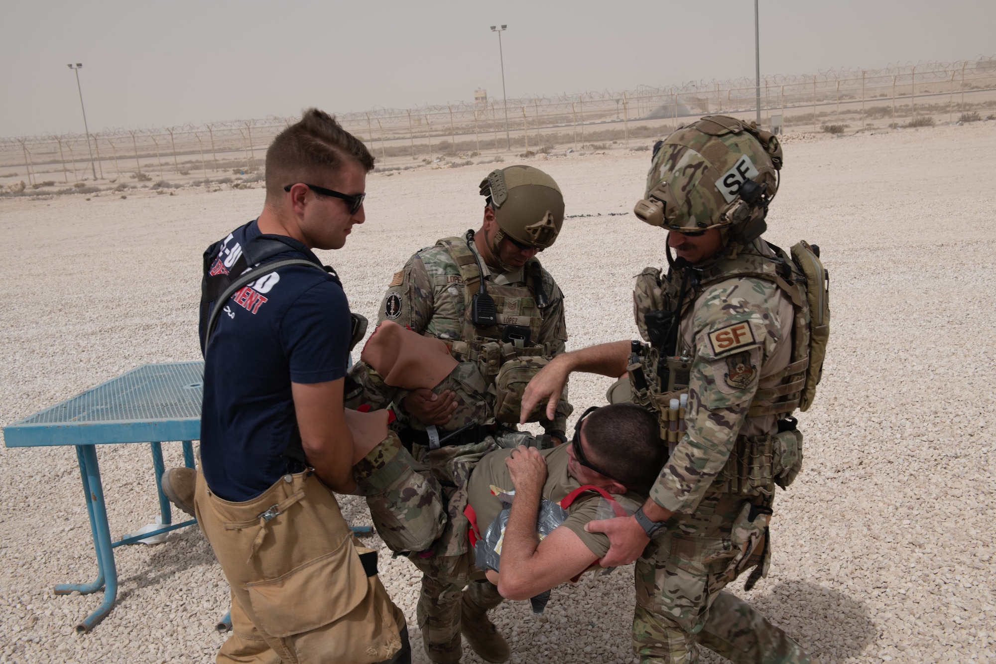 U.S. Air Force 379th Expeditionary Security Forces Squadron members work with a U.S. Air Force firefighter from the 379th Expeditionary Civil Engineering Squadron to transport a simulated casualty to a safer location during an exercise on Al Udeid Air Base, Qatar, June 27, 2022. Casualties are transported to hospitals as soon as possible following first aid treatment. (U.S. Air National Guard photo by Airman 1st Class Constantine Bambakidis)