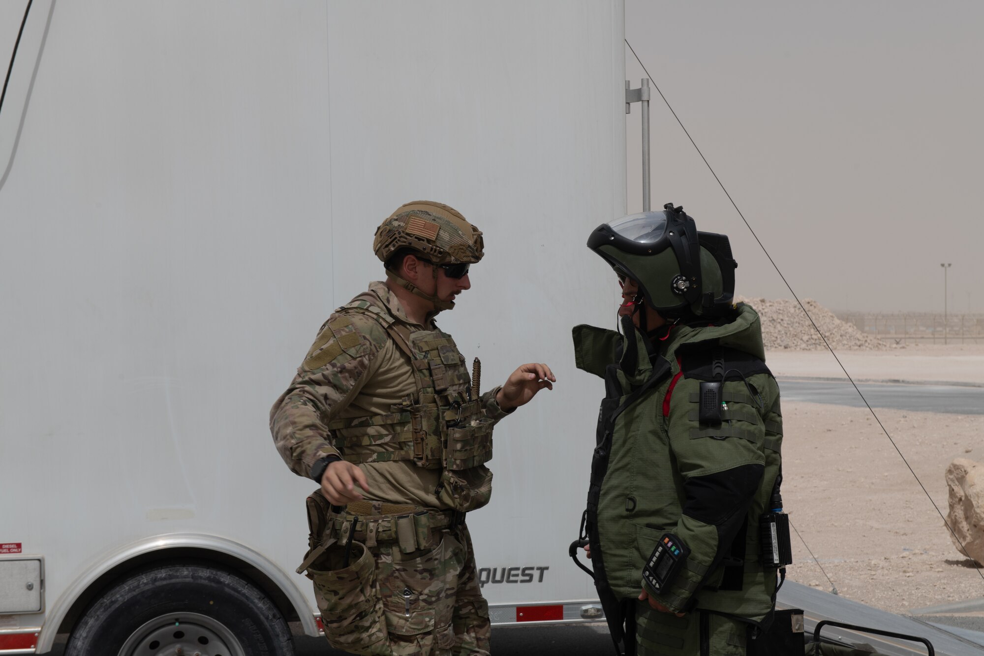 U.S. Air Force Tech. Sgt. Kyle Doran, an explosive ordinance disposal specialist with the 379th Expeditionary Civil Engineering Squadron, assists U.S. Air Force Staff Sgt. George Cochran as he dons a protective suit during an exercise on Al Udeid Air Base, Qatar, June 27, 2022. The armored suit helps protect EODs while working with explosive ordinance. (U.S. Air National Guard photo by Airman 1st Class Constantine Bambakidis)