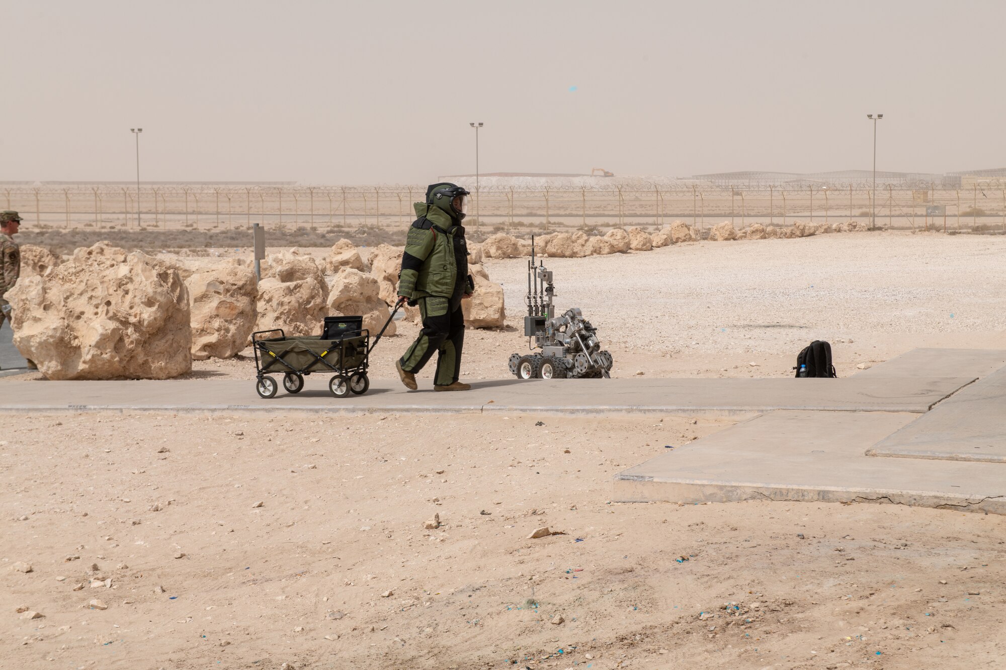 U.S. Air Force Staff Sgt. George Cochran, an explosive ordinance disposal specialist with the 379th Expeditionary Civil Engineering Squadron, walks with a cart full of equipment during an exercise on Al Udeid Air Base, Qatar, June 27, 2022. EODs work with a variety of tools in order to resolve dangerous situations effectively. (U.S. Air National Guard photo by Airman 1st Class Constantine Bambakidis)