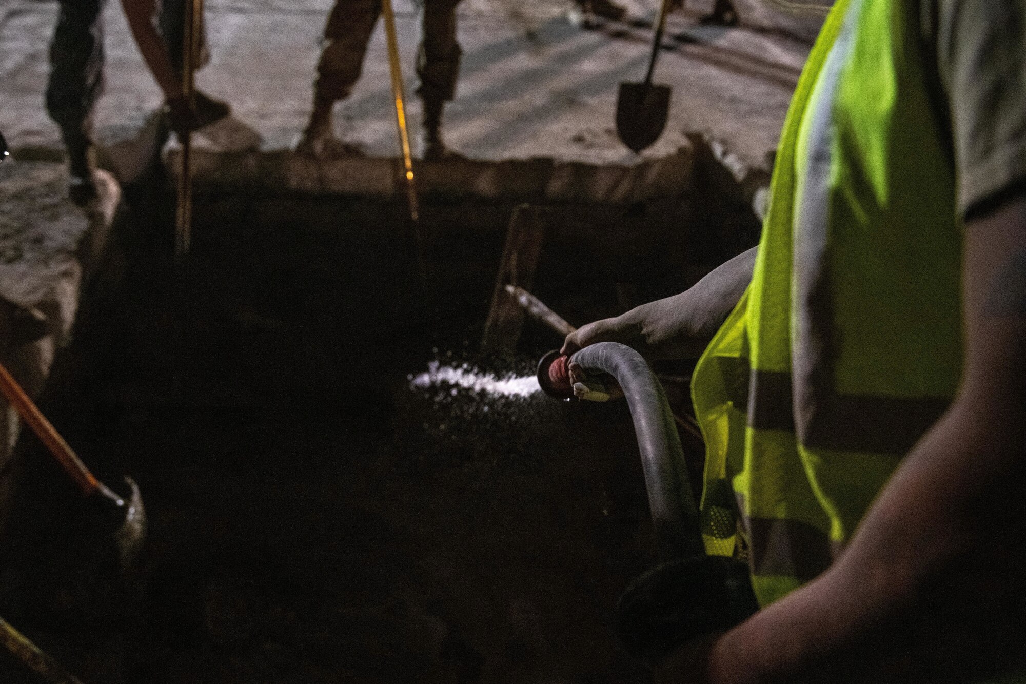 A civil engineer with the U.S. Air Force 379th Expeditionary Civil Engineer Squadron sprays water into a crater during a flight line repair exercise on Al Udeid Air Base, Qatar, June 27, 2022. The goal of rapid flight line repair is to ensure a flight line can resume aircraft operations as quickly as possible after sustaining damage. (U.S. Air National Guard photo by Airman 1st Class Constantine Bambakidis)