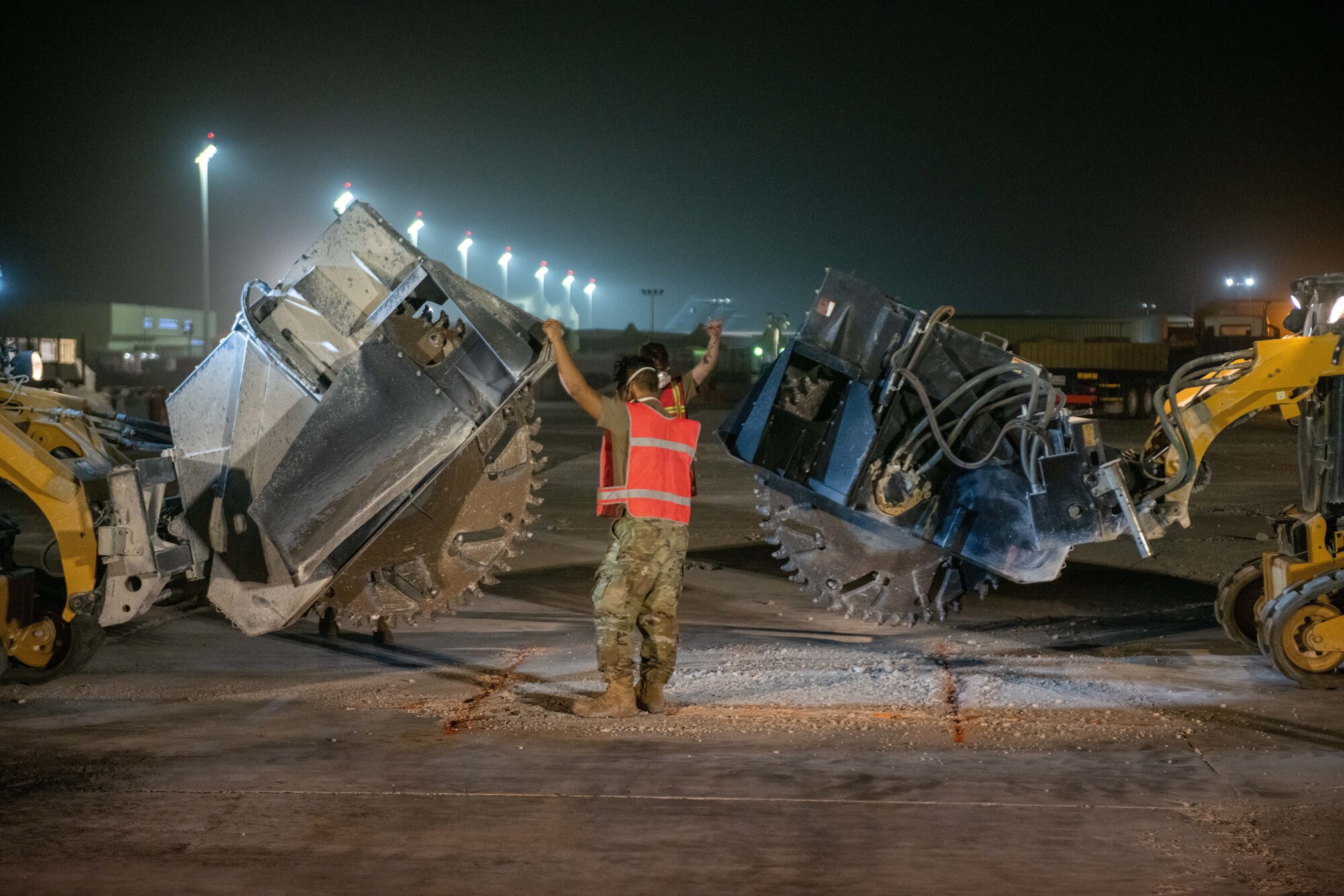 U.S. Air Force engineer assistants with the 379th Expeditionary Civil Engineer Squadron guide pavement cutting machinery during a flight line repair exercise on Al Udeid Air Base, Qatar, June 27, 2022. After being marked, the damaged pavement is cut out then refilled. (U.S. Air National Guard photo by Airman 1st Class Constantine Bambakidis)
