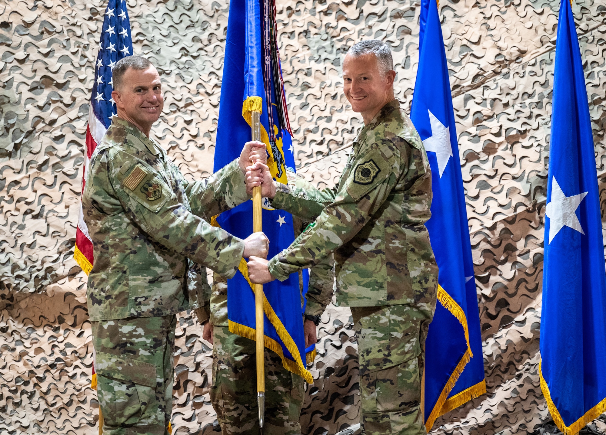 U.S. Air Force Lt. Gen. Gregory Guillot, Ninth Air Force (Air Forces Central) commander, exchanges the 332d Air Expeditionary Wing guidon with U.S. Air Force Brig. Gen. R. Ryan Messer, 332d AEW incoming commander, during a change of command ceremony at an undisclosed location in Southwest Asia, July 3, 2022. A change of command ceremony is a tradition that represents a formal transfer of authority and responsibility from the outgoing commander to the incoming commander. (U.S. Air Force photo by Master Sgt. Christopher Parr)
