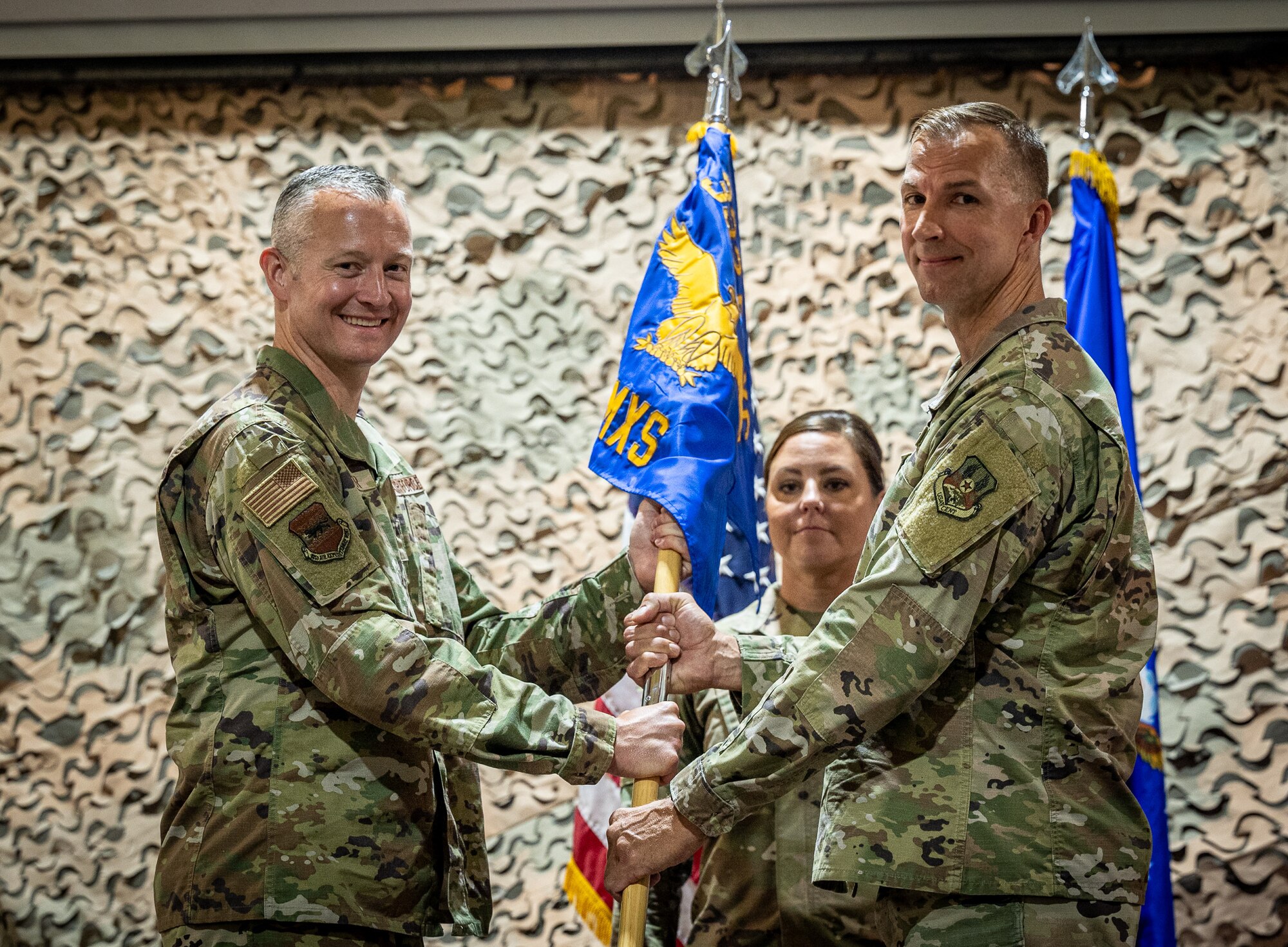 U.S. Air Force Brig. Gen. Ryan Messer, 332d Air Expeditionary Wing commander, exchanges the 332d Expeditionary Maintenance Squadron guidon with U.S. Air Force Lt. Col. Lee R. Russell, 332d EXMS incoming commander, during a change of command ceremony at an undisclosed location in Southwest Asia, July 3, 2022. A change of command ceremony is a tradition that represents a formal transfer of authority and responsibility from the outgoing commander to the incoming commander. (U.S. Air Force photo by Master Sgt. Christopher Parr)