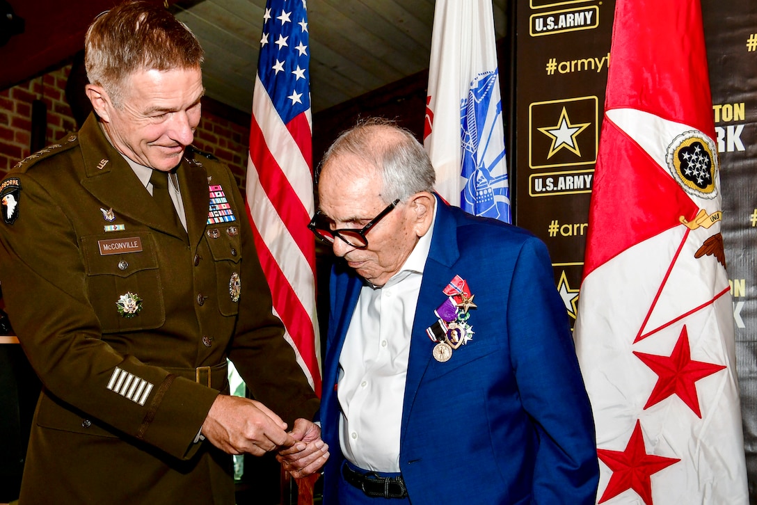 Army general hands an object to a World War II veteran.