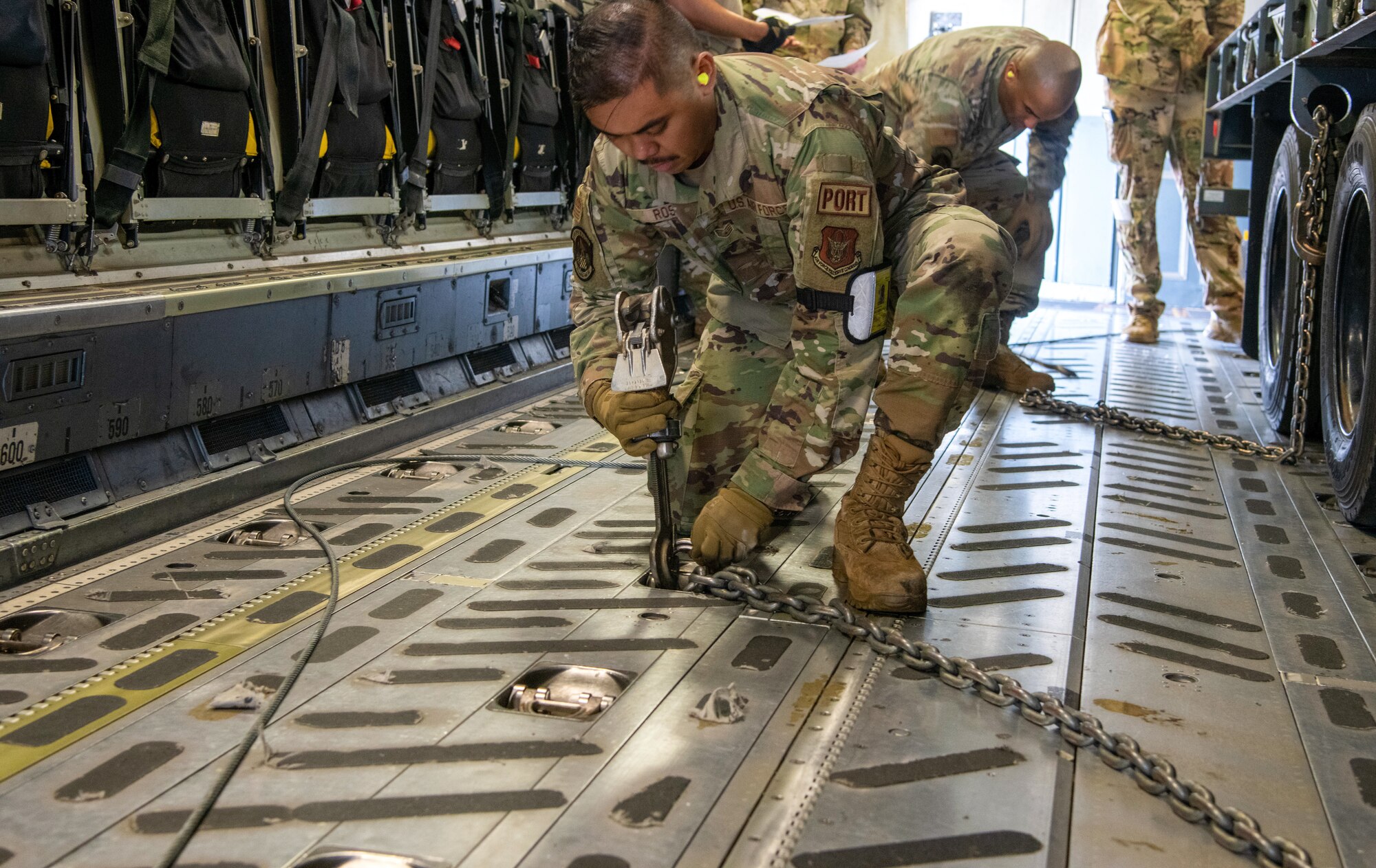 Airman chains a tracker trailer on an aircraft.