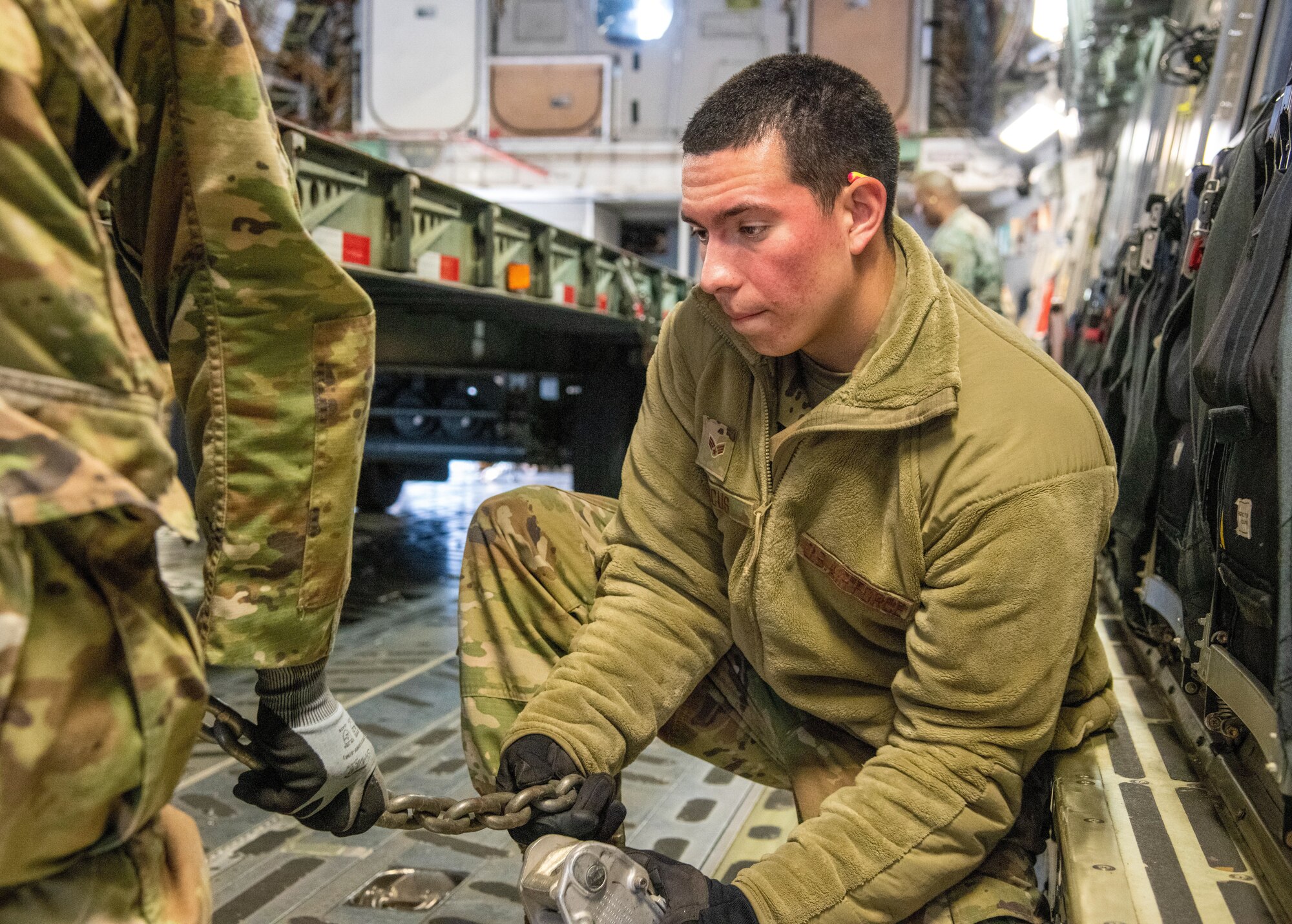 Airman chains a tracker trailer on an aircraft.