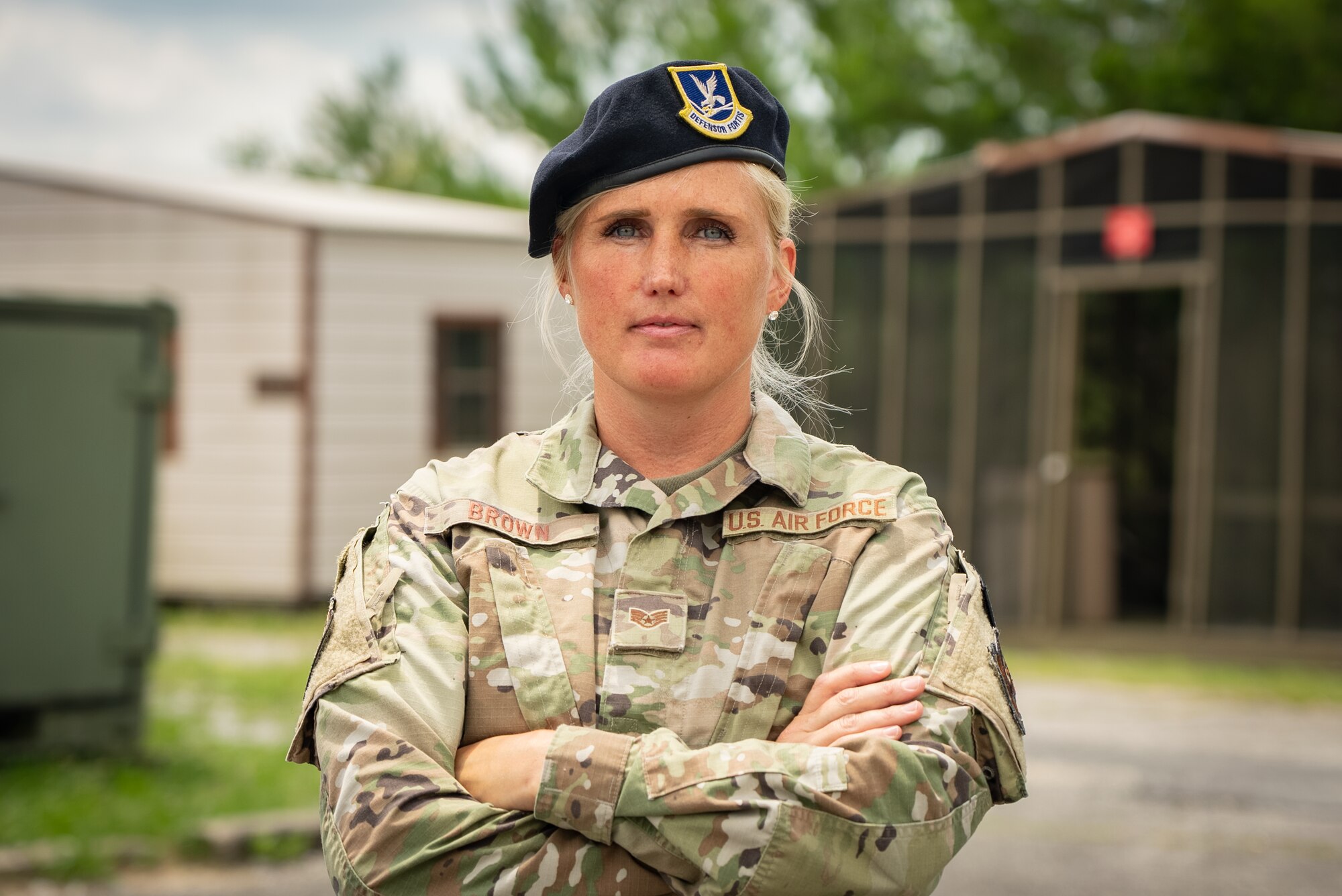 Female Airman wearing a beret poses with arms crossed.