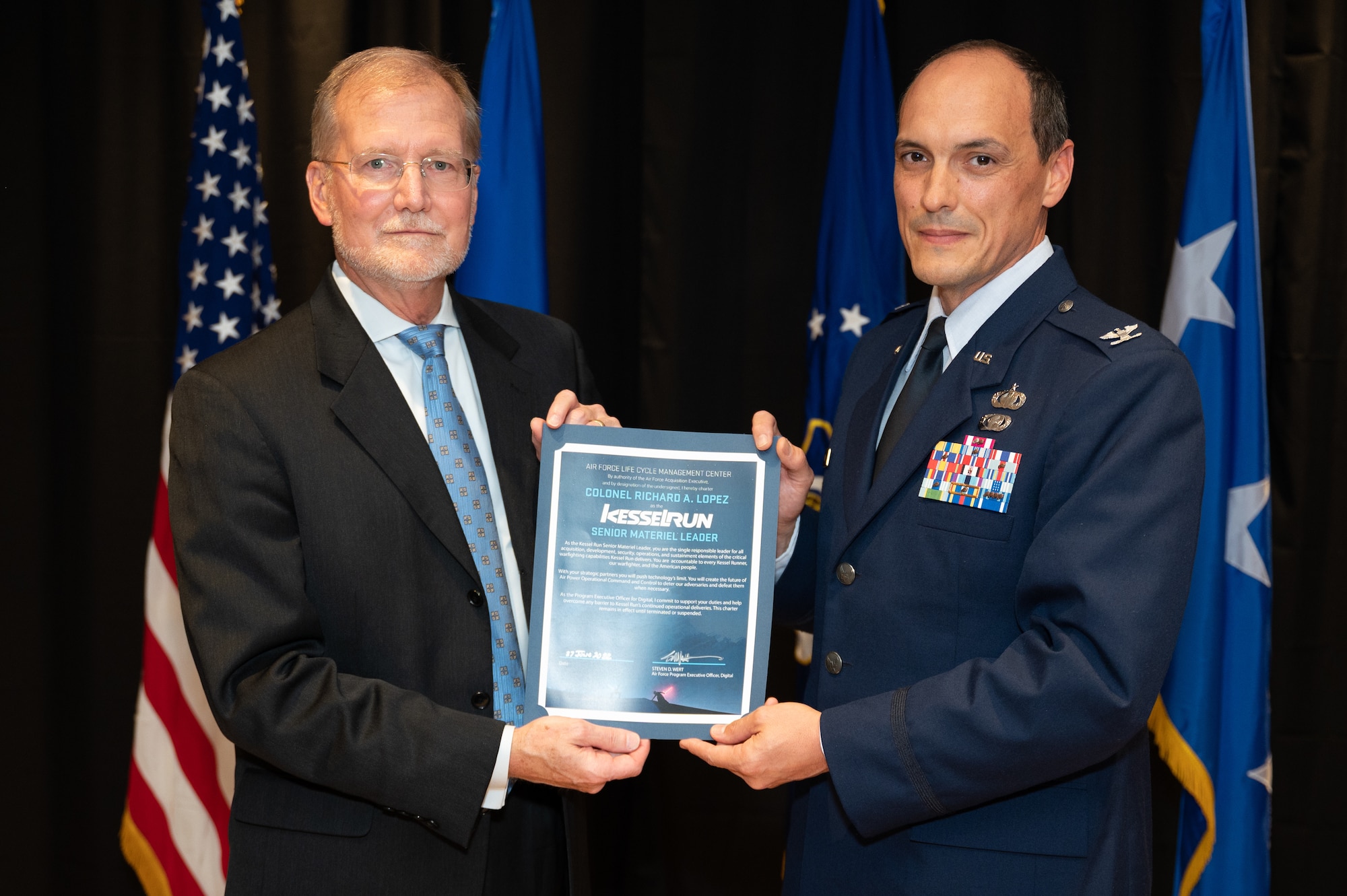 Steven Wert, program executive officer, Digital, presents a certificate to Col. Richard Lopez, Kessel Run senior materiel leader, during a transition ceremony at the unit’s headquarters in Boston, June 27. Kessel Run transitioned from a detachment to a division of Air Force Life Cycle Management Center’s Digital Directorate. (U.S. Air Force photo by Jerry Saslav)