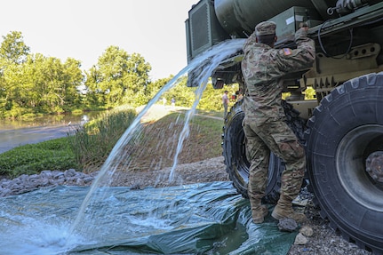 Kentucky Army National Guard Pfc. Adrian Shifflett with the 2061st Multi Role Bridge Company opens the water spout on his Army Palletized Load System (PLS) vehicle during a mission in Marion, Kentucky, July 1, 2022. About 20 Kentucky Guardsmen were called in to help respond to a water shortage.