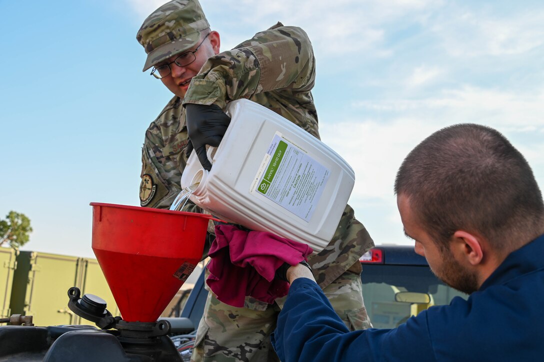 U.S. Air Force Staff Sgt. Vincent Sarver (left), 97th Civil Engineer Squadron (CES) pest management noncommissioned officer in charge, and Nicholas Sharp, 97th CES pest management specialist, pour pesticide into a fog machine at Altus Air Force Base (AAFB), Oklahoma, June 27, 2022. Mosquito fogging is a yearly process completed by 97th CES Airmen for AAFB and contractors for on-base housing. (U.S. Air Force photo by Senior Airman Kayla Christenson)