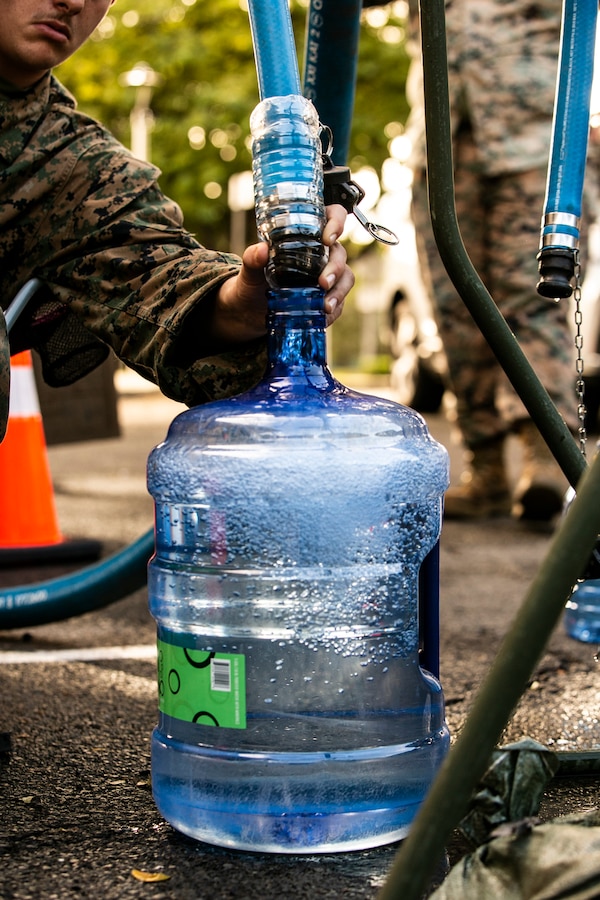 U.S. Marines with Combat Logistics Battalion 3, 3rd Marine Logistics Group (MLG), and U.S. Army Soldiers with 524th Division Sustainment Support Battalion, 1st Cavalry Division, operate a water distribution point outside of Catlin School, Oahu, Hawaii, Dec. 12, 2021. U.S. Marines with 3rd MLG, as part of Task Force KULEANA, are providing support services such as drinking water, field expedient showers and laundry facilities to the residents of Joint Base Pearl Harbor-Hickam affected by the ongoing water issue. 3rd MLG, based out of Okinawa, Japan, is a forward deployed combat unit that serves as III Marine Expeditionary Force’s comprehensive logistics and combat service support backbone for operations throughout the Indo-Pacific area of responsibility. (U.S. Marine Corps photo by Sgt. Hailey D. Clay)