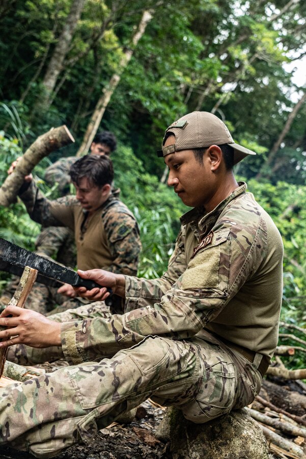 U.S. Air Force Senior Airman Christopher Ramos, an explosive ordnance technician with the 99th Civil Engineer Squadron, splits firewood during Jungle Crab 22 at Jungle Warfare Training Center, Okinawa, Japan, June 24, 2022. During Jungle Crab 22 EOD Marines prepared to support Expeditionary Advanced Base Operations by practicing survival methods in areas where logistical support may not be available. 3rd MLG, based out of Okinawa, Japan, is a forward deployed combat unit that serves as III Marine Expeditionary Force’s comprehensive logistics and combat service support backbone for operations throughout the Indo-Pacific area of responsibility. (U.S. Marine Corps photo by Cpl. Moises Rodriguez)