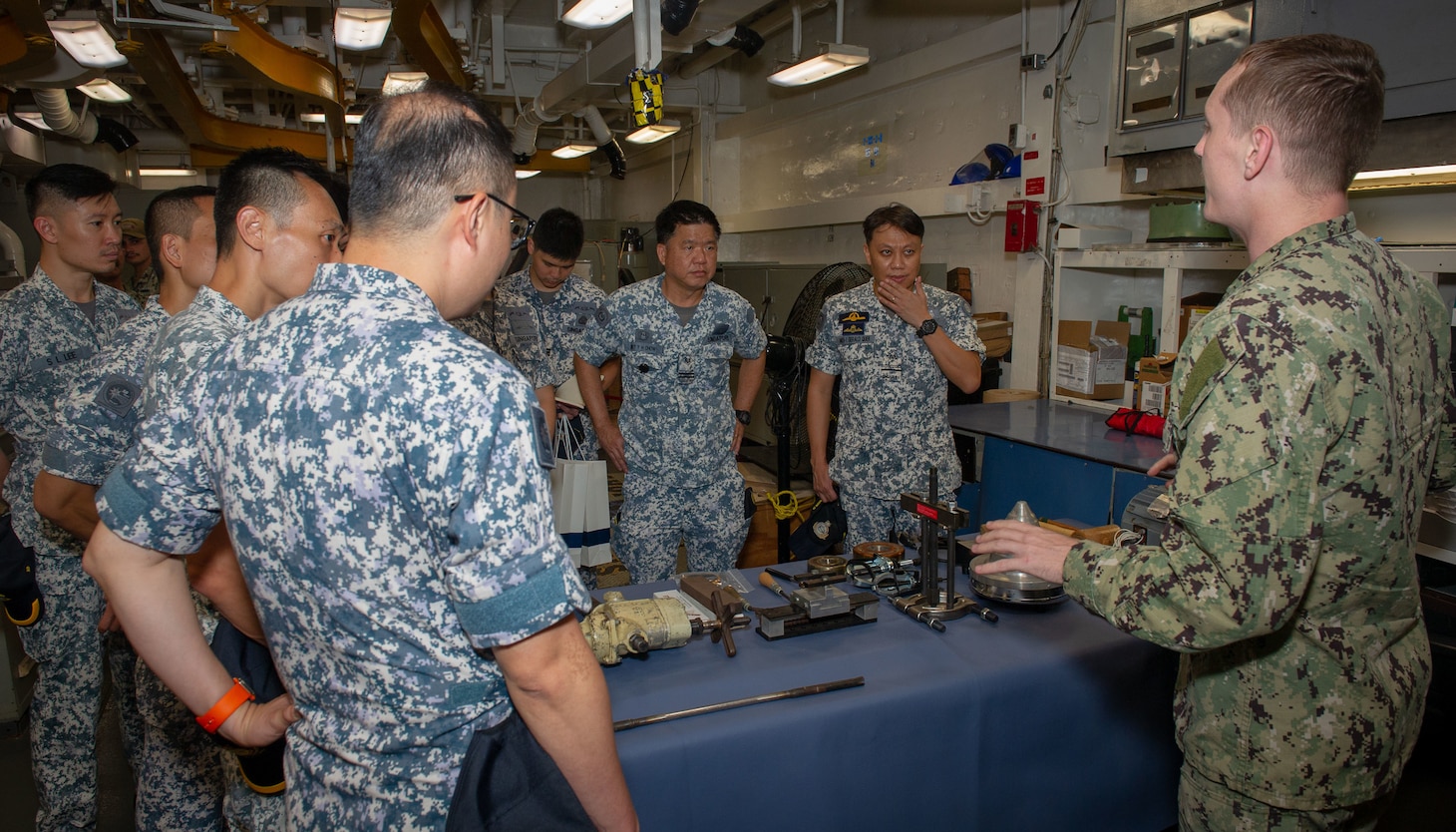 SINGAPORE (June 29, 2022) – U.S. Navy Electrician’s Mate 2nd Class Matthew Hendricks, assigned to the Emory S. Land-class submarine tender USS Frank Cable (AS 40), explains the ship’s repair capabilities to Sailors of the Republic of Singapore Navy during a tour of the ship, June 29, 2022. Frank Cable is currently on patrol conducting expeditionary maintenance and logistics in support of national security in the U.S. 7th Fleet area of operations. (U.S. Navy photo by Mass Communication Specialist 3rd Class Henry Liu)