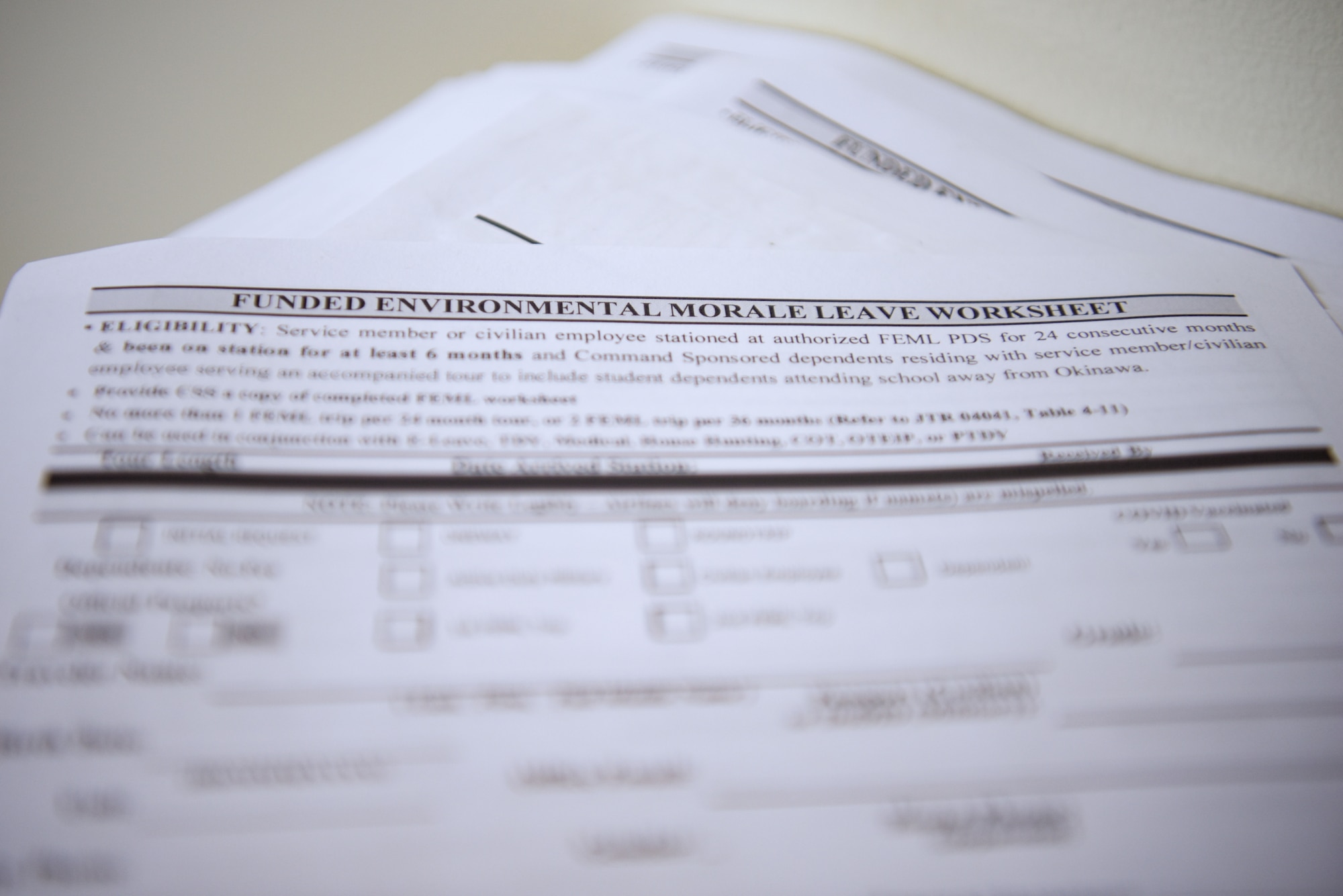 A blank Funded Environmental and Morale Leave worksheet lies on top of a stack of papers.