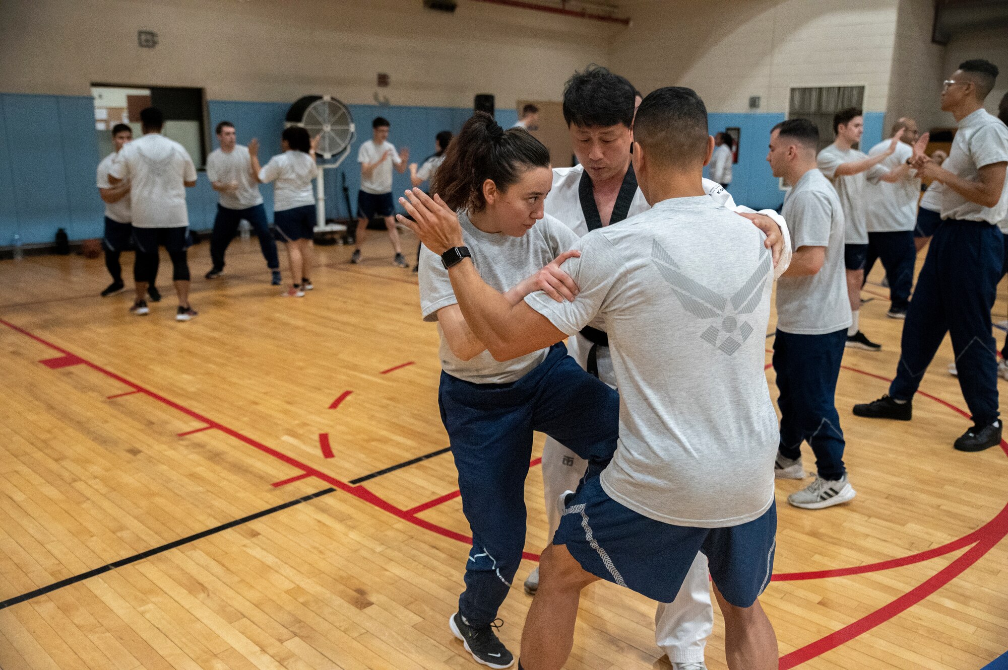 Airmen from the 51st Mission Support Group are guided by Master Doyoung Jang, Taekwondo Promotion Foundation, on how to execute proper knee strike offense motions during an MSG physical training session at Osan Air Base, Republic of Korea, June 30, 2022.