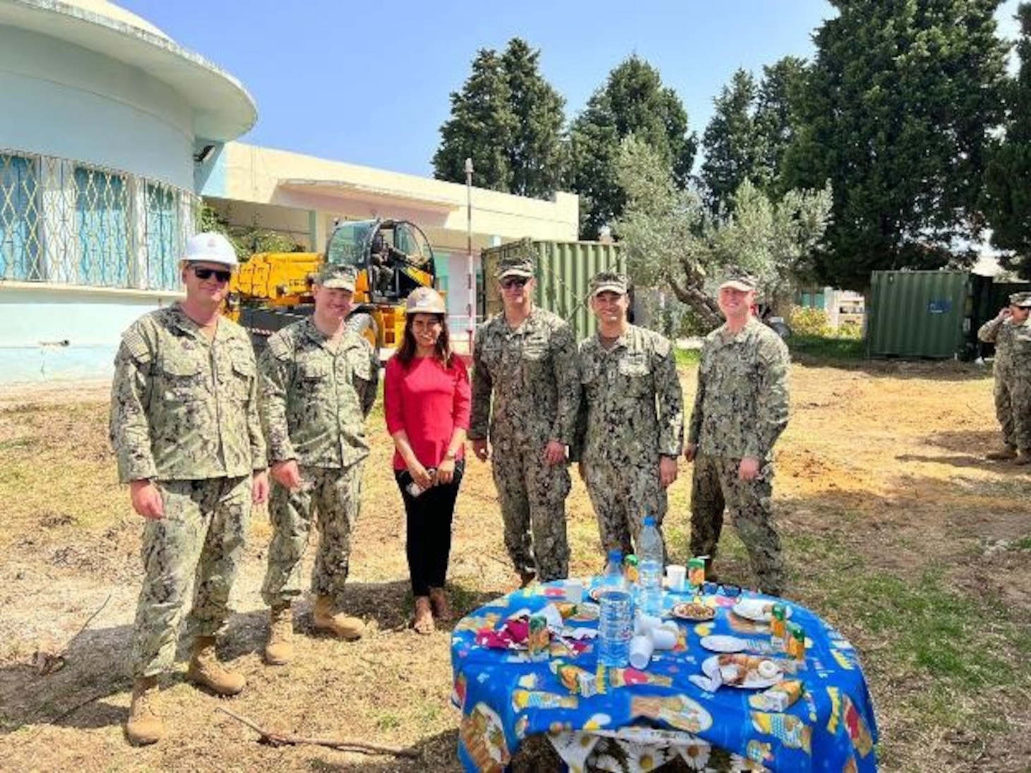 (June 7, 2022) U.S. Navy Seabees assigned to Naval Mobile Construction Battalion 133 pose for a photo with a teacher Reem Glai Hassen at ground breaking ceremony to begin the construction of a new 130 square meter, two-room kindergarten building with a bathroom at the local elementary school in Bizerte, Tunisia on June 7, 2022. Phoenix Express 22, conducted by U.S. Naval Forces Africa, is a maritime exercise designed to improve cooperation among participating nations in order to increase maritime safety and security in the Mediterranean.