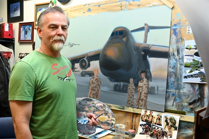 Photo of Darby Perrin standing in front of one of his paintings.