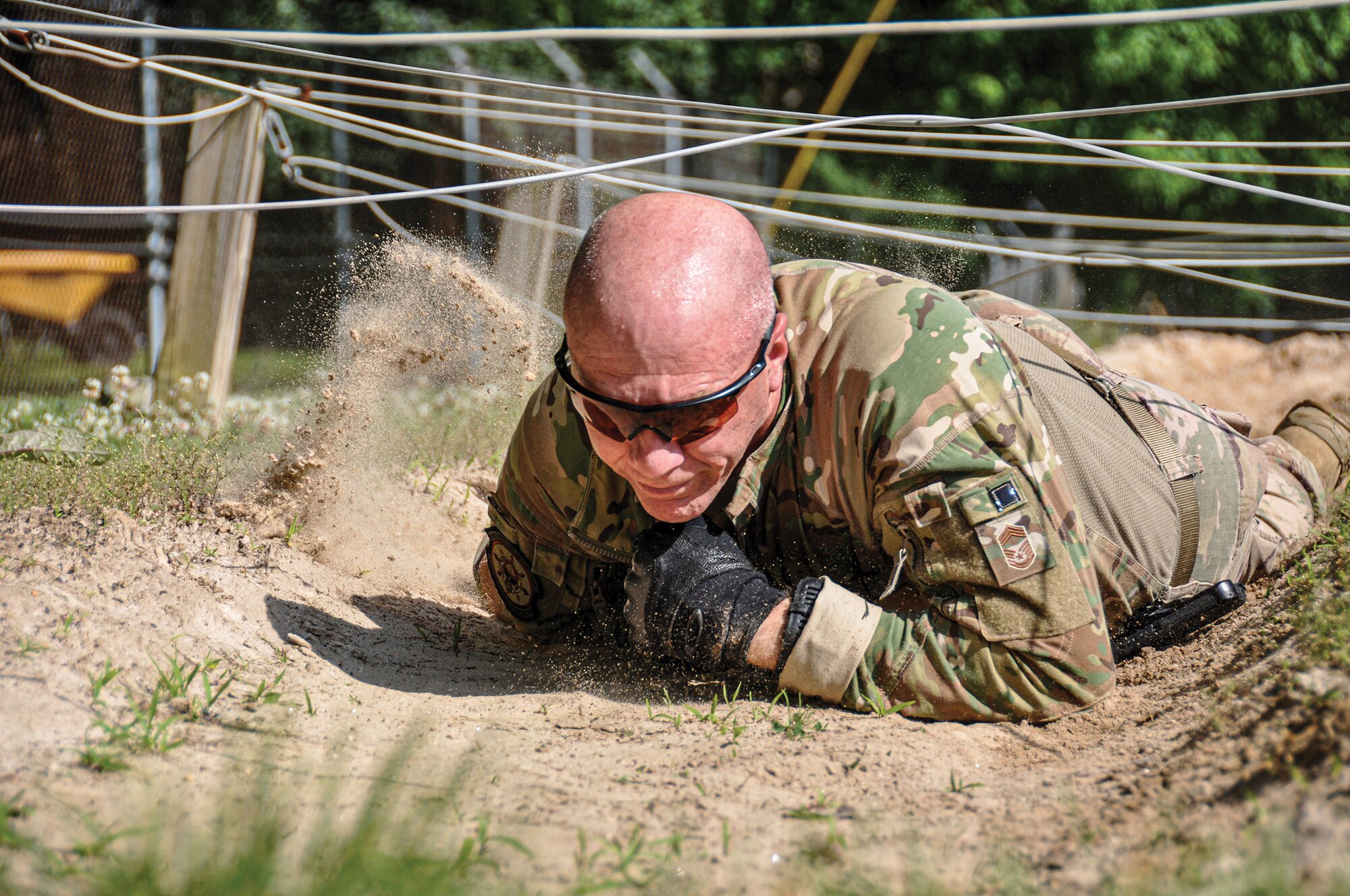 Chief Master Sgt. James Kirklin, 445th Security Forces Squadron security forces manager, low crawls through a sand pit under suspended wire during a nine-part obstacle course at Camp Dawson, West Virginia, June 8, 2022. The senior enlisted leader of the 445th SFS joined a four-person fire team to participate in the training event, which occurred just one day after the squadron completed a nearly 10-mile land navigation course through the West Virginia mountains.