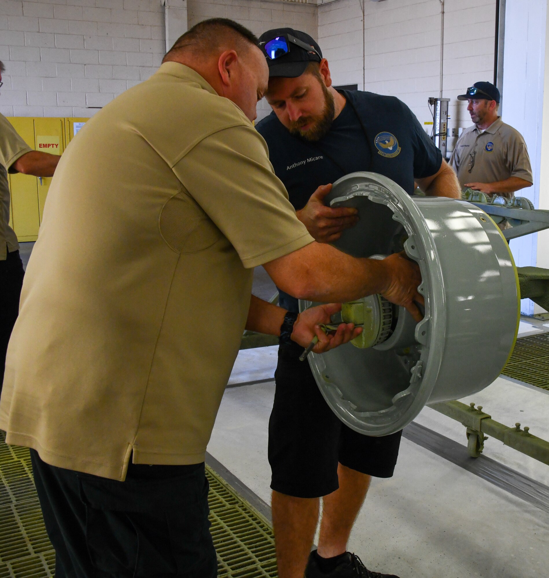 Todd Dennison (left), 97th Aircraft Maintenance Squadron superintendent, and Anthony Micare,97th Maintenance Squadron (MXS) aircraft painter, load a KC-46 Pegasus wheel onto a “paint rotisserie wheel rack” at Altus Air Force Base, Oklahoma, June 24, 2022. 97th MXS maintainers manufactured the painting fixture in order to increase production. (U.S. Air Force photo by Airman 1st Class Miyah Gray)