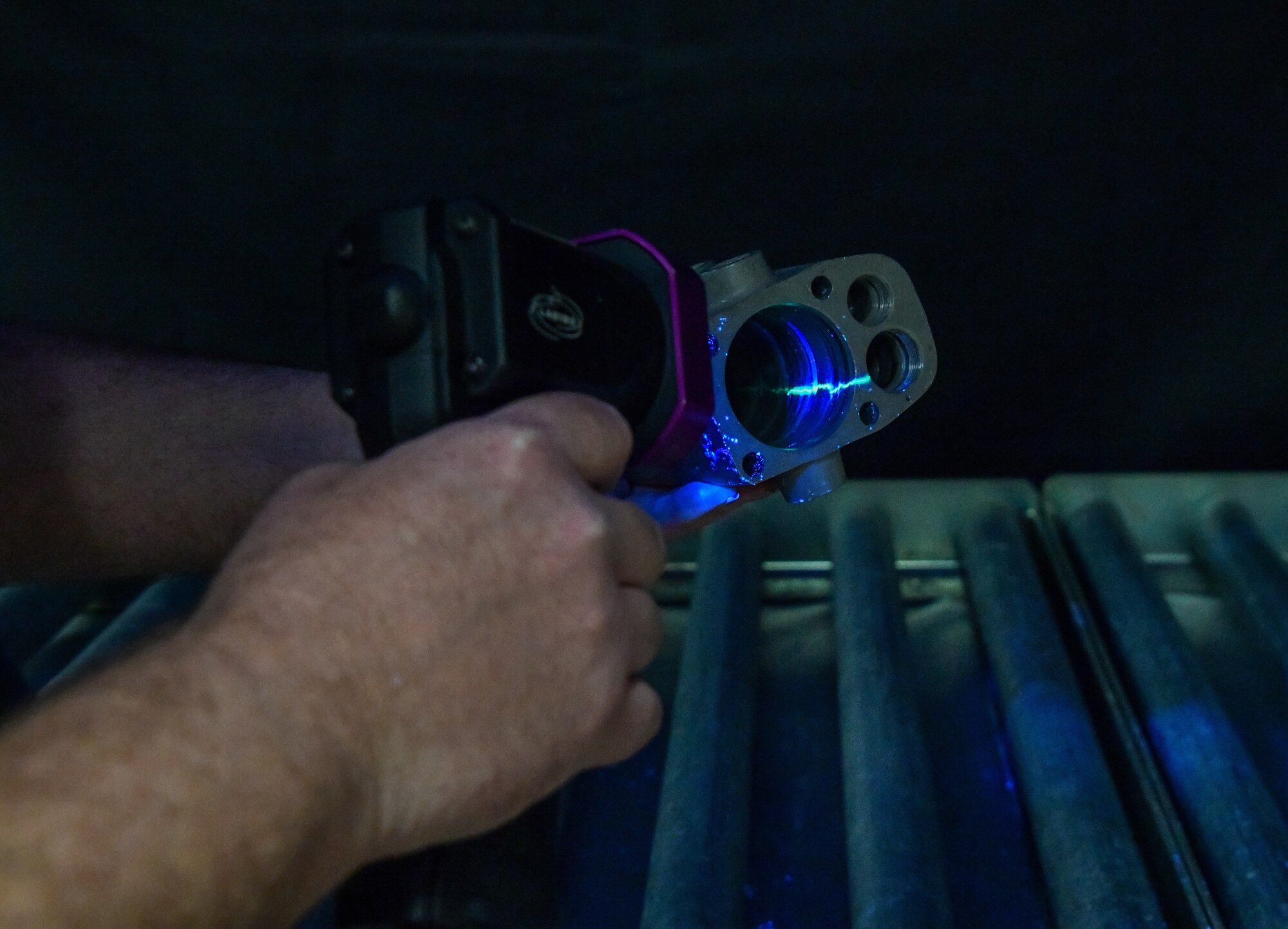 Gordon Tucker, 97th Maintenance Squadron nondestructive inspection tester, checks for cracks in a KC-135 spoiler actuator using a dye penetrant solution and ultraviolet light at Altus Air Force Base, Oklahoma, June 24, 2022. The solution seeps into cracks in the equipment, making them easily identifiable. (U.S. Air Force photo by Airman 1st Class Miyah Gray)