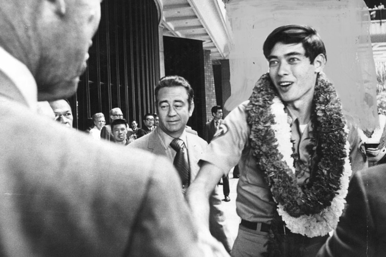 A solider wearing a lei stands in a crowd