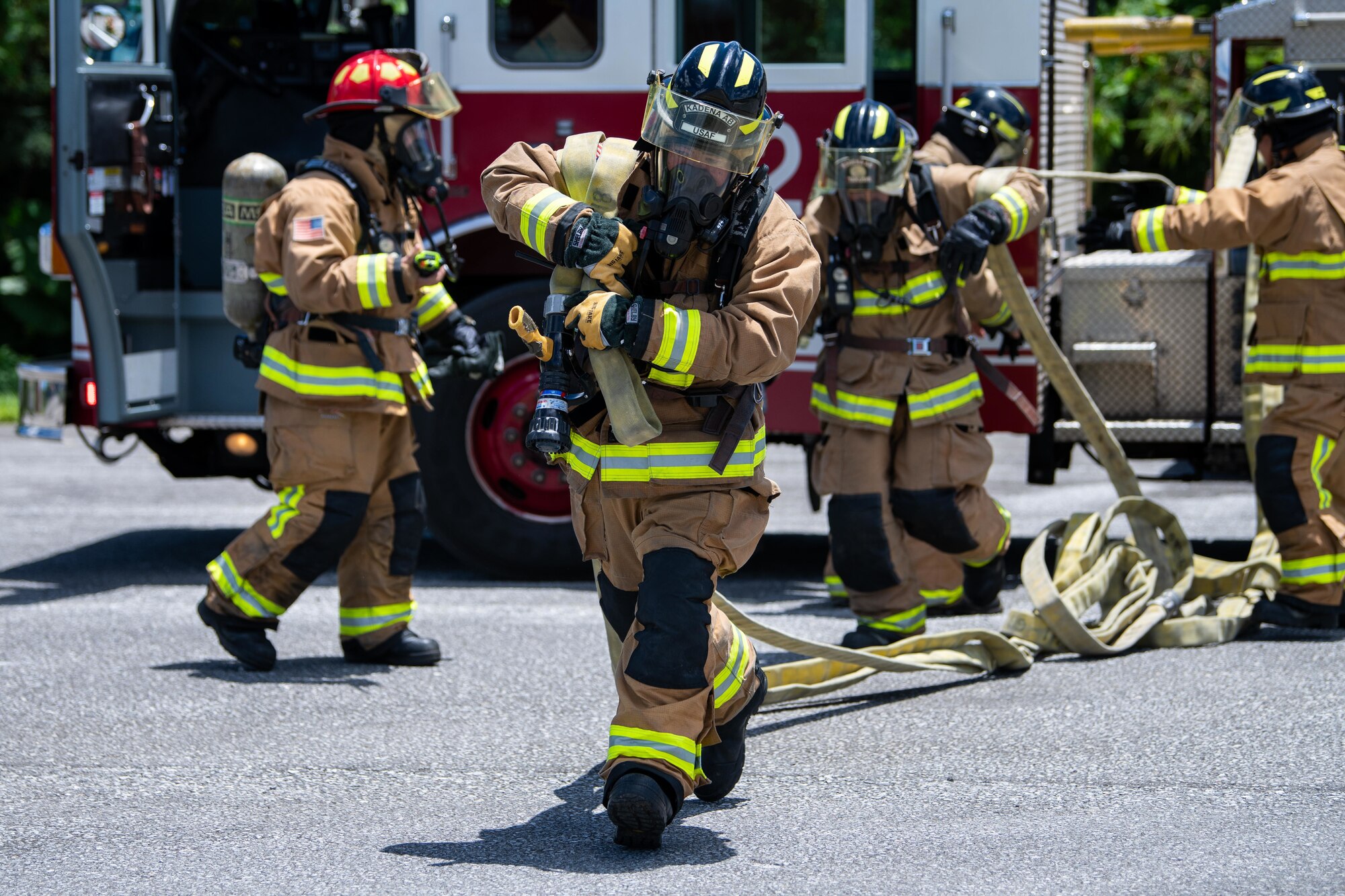 Firefighters carry a hose.